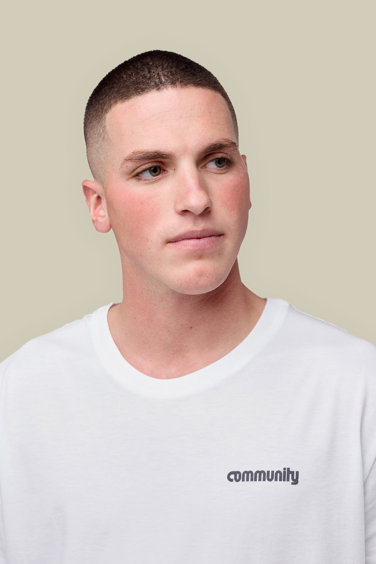 Portrait of white male wearing short sleeve crew neck white t shirt with black community logo on left of chest