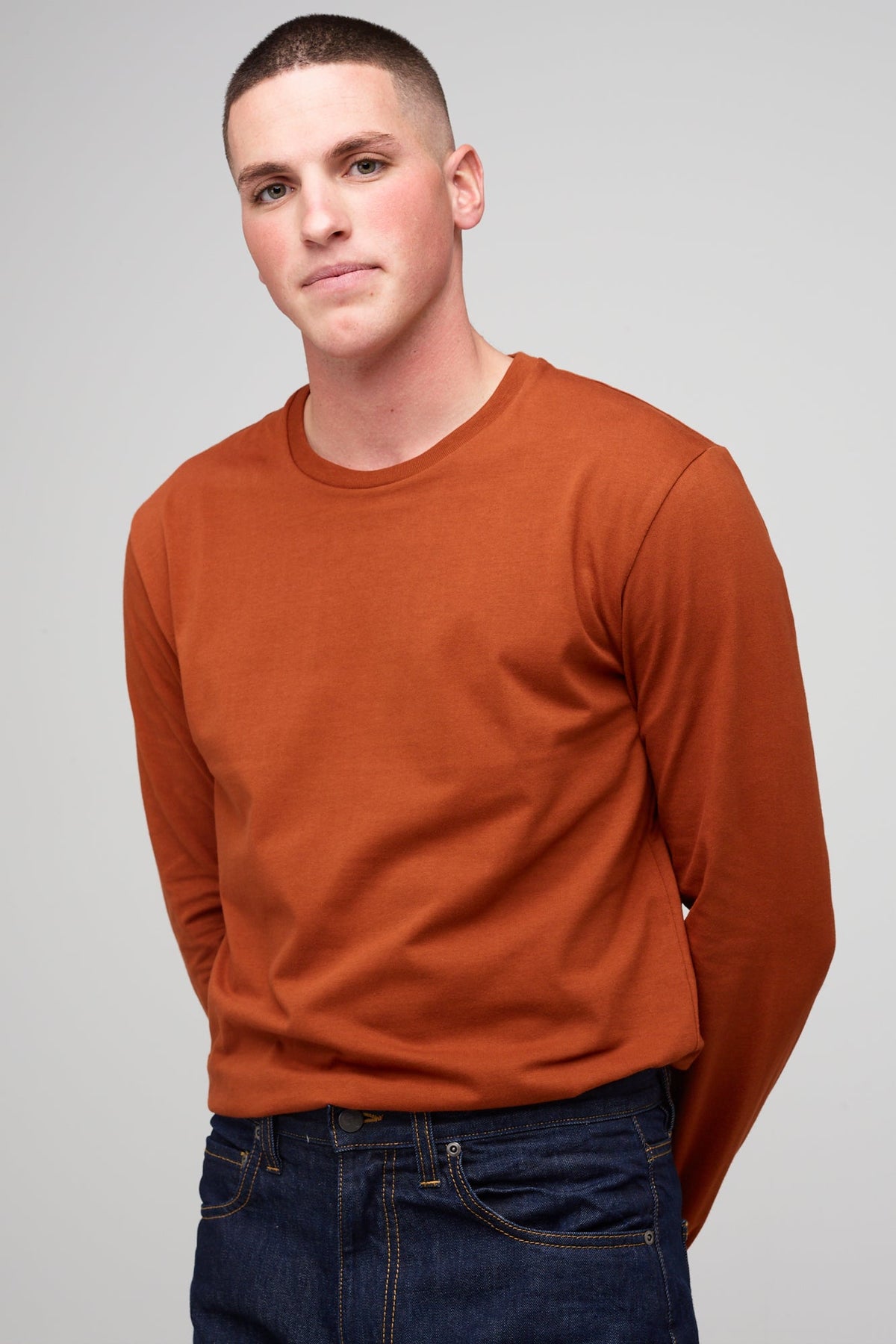 Brunete, white male wearing long sleeve t-shirt in cinnamon tucked into denim jeans