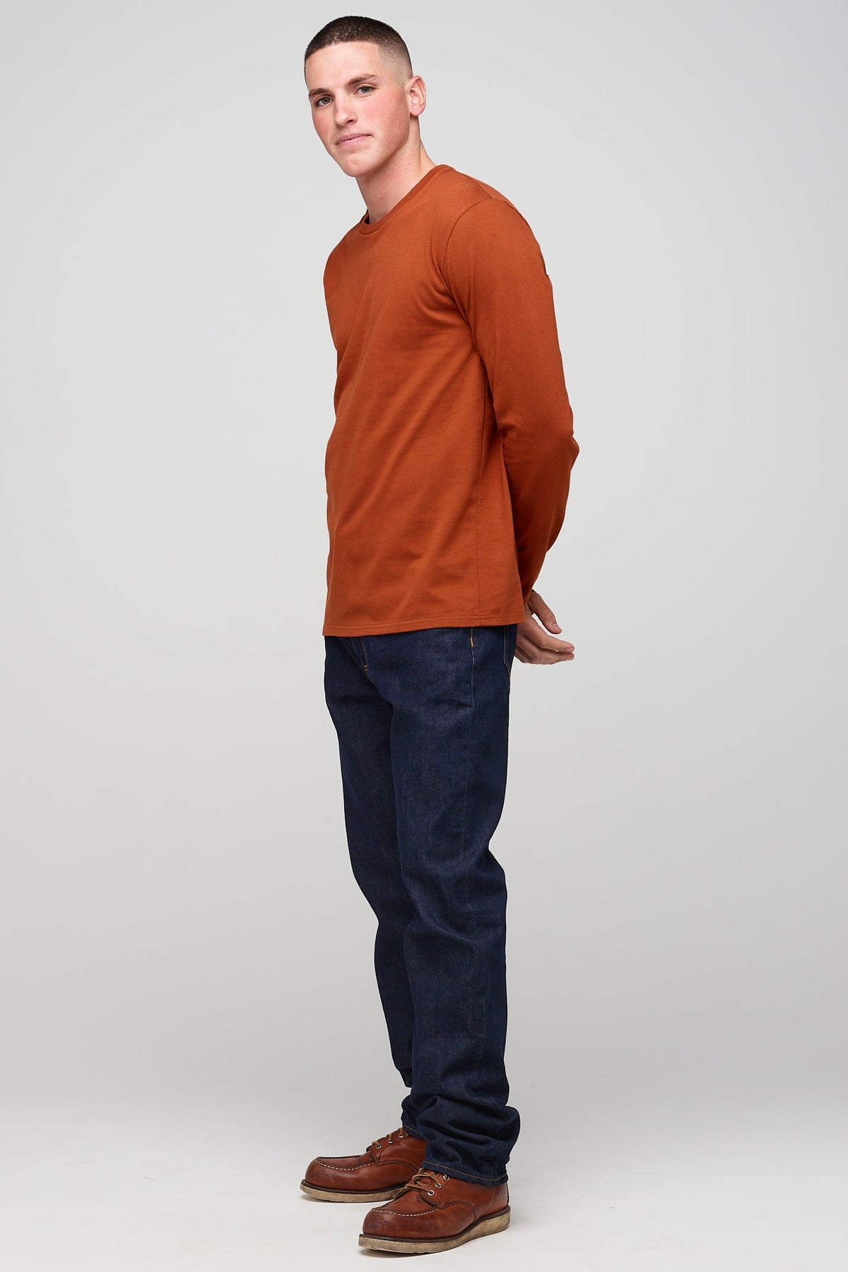 Brunete, white male wearing long sleeve t-shirt in cinnamon worn with denim jeans 