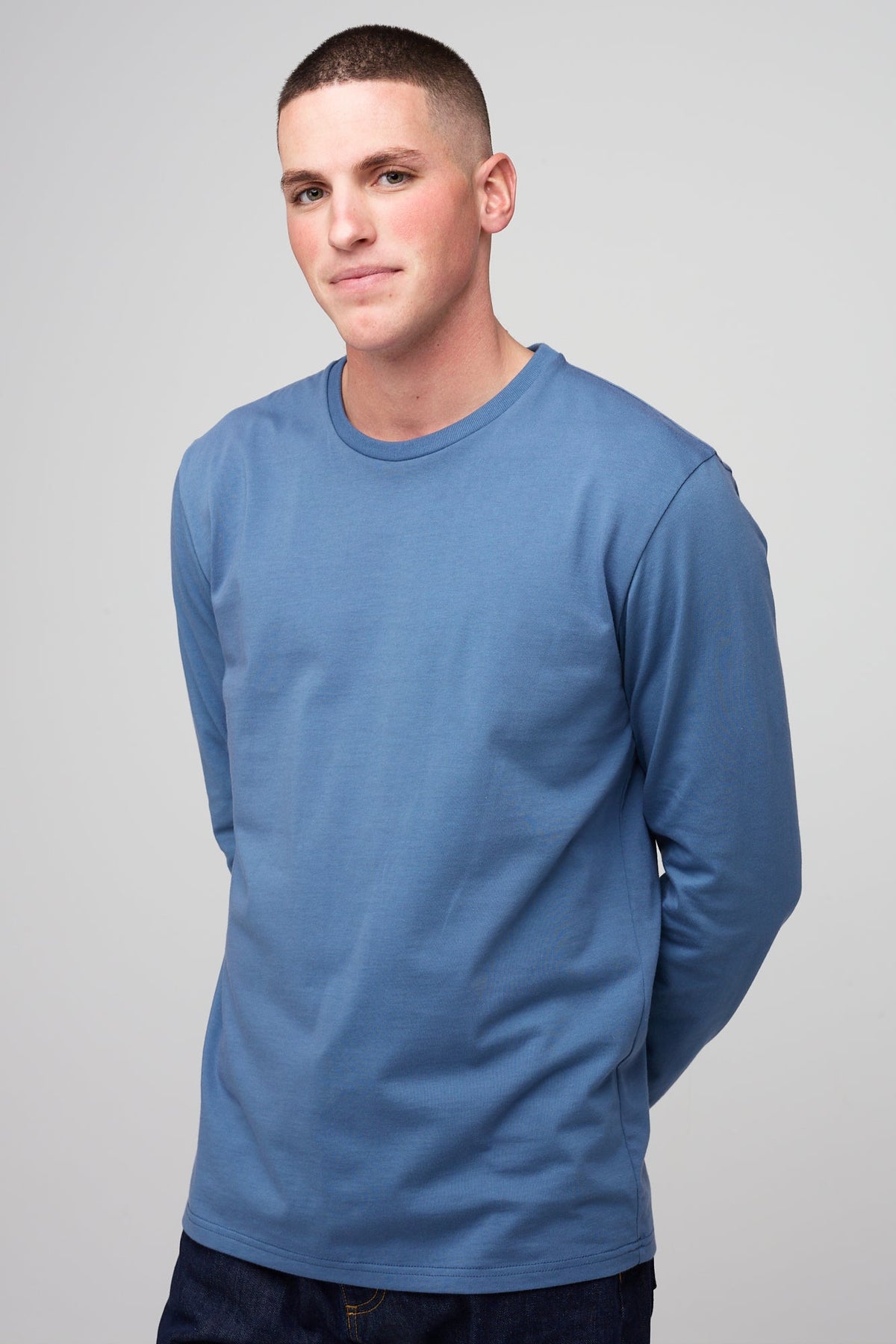 Brunette white male wearing long sleeve t-shirt in RAF blue styled with denim jeans 