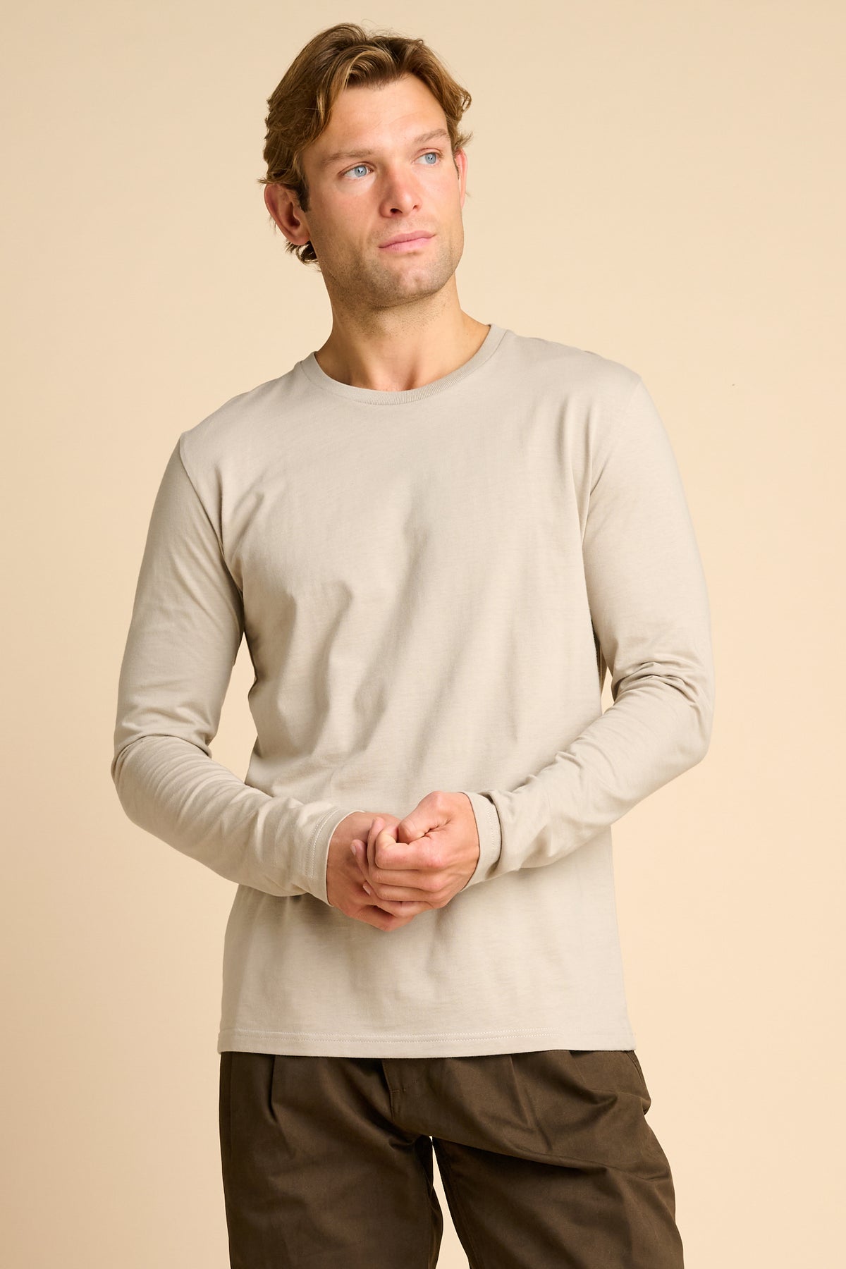 Man wearing stone coloured t shirt against beige background.