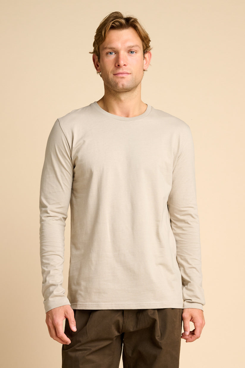 Man wearing stone coloured t shirt against beige background.