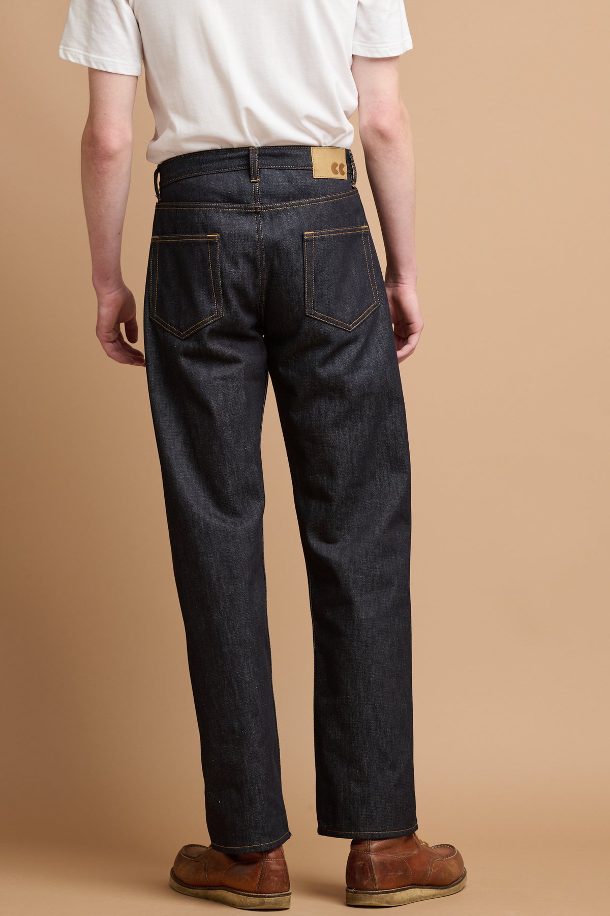The back of male wearing community clothing selvedge denim jeans.