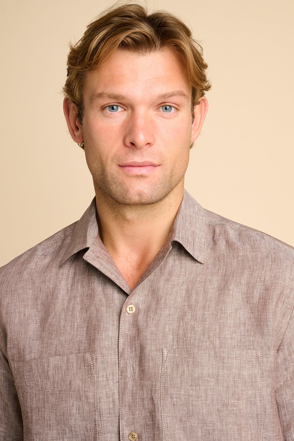 Man wearing a brown shirt against a beige background