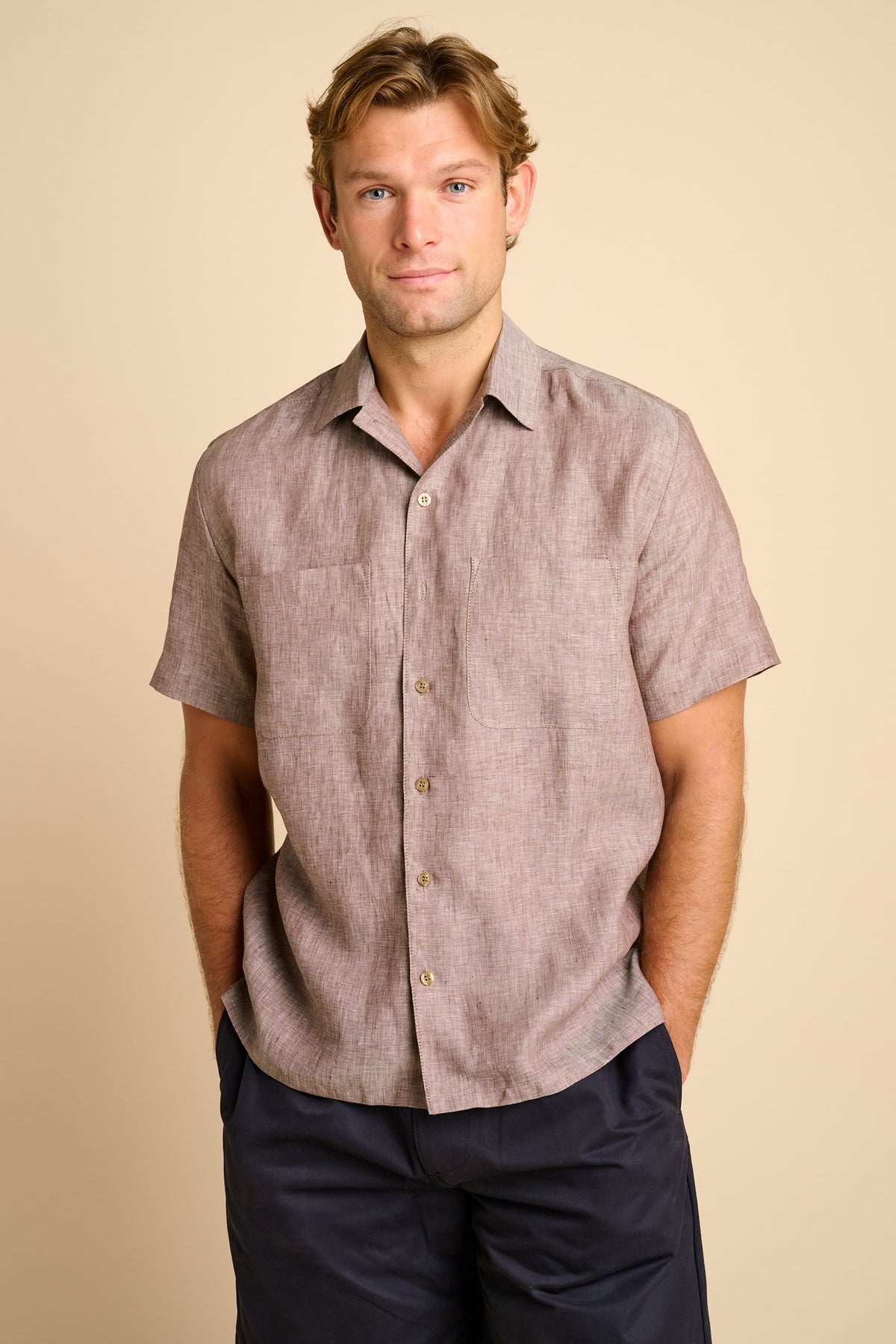 Man wearing a brown short-sleeve shirt against a beige background.