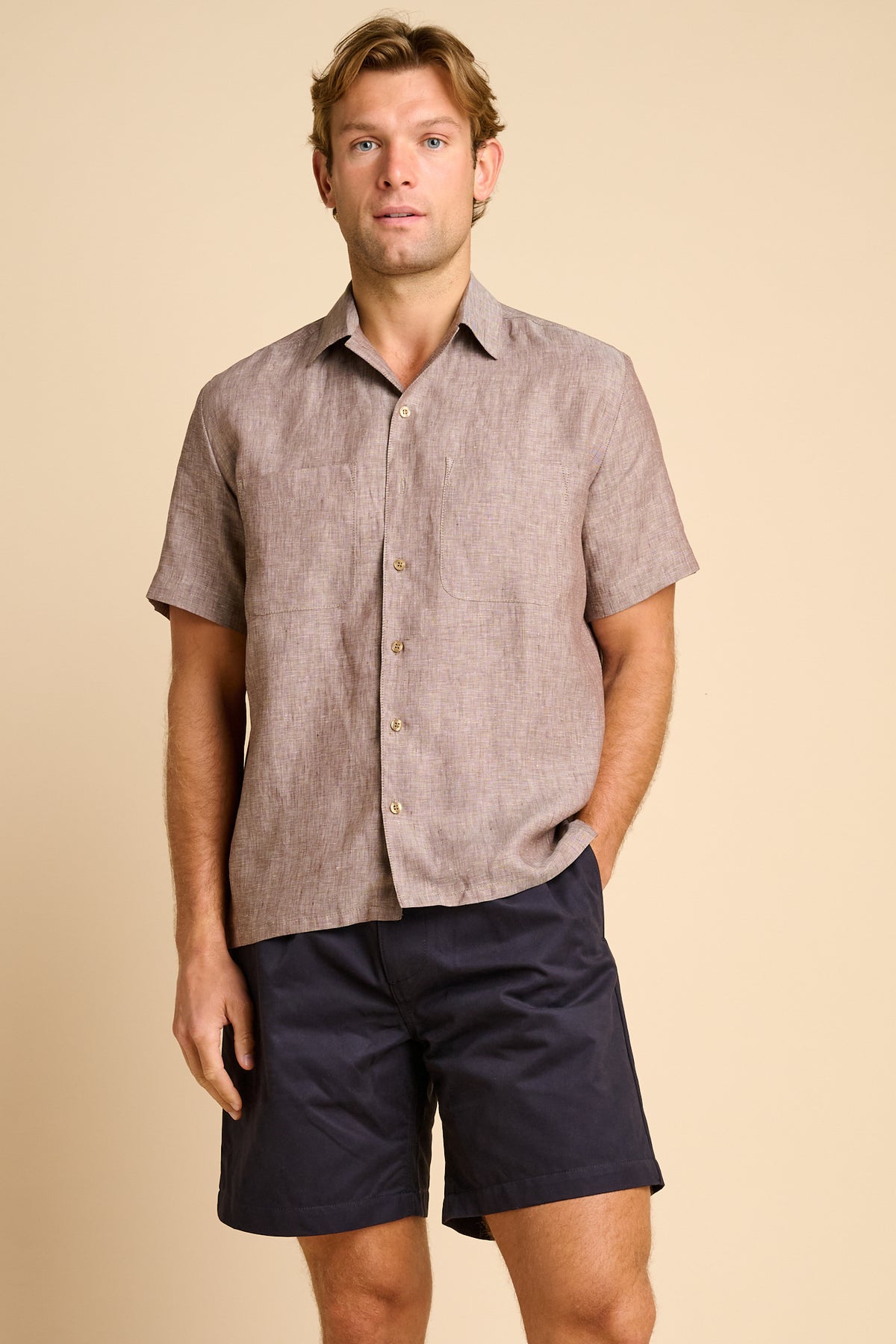 Man wearing a brown short-sleeve shirt against a beige background.