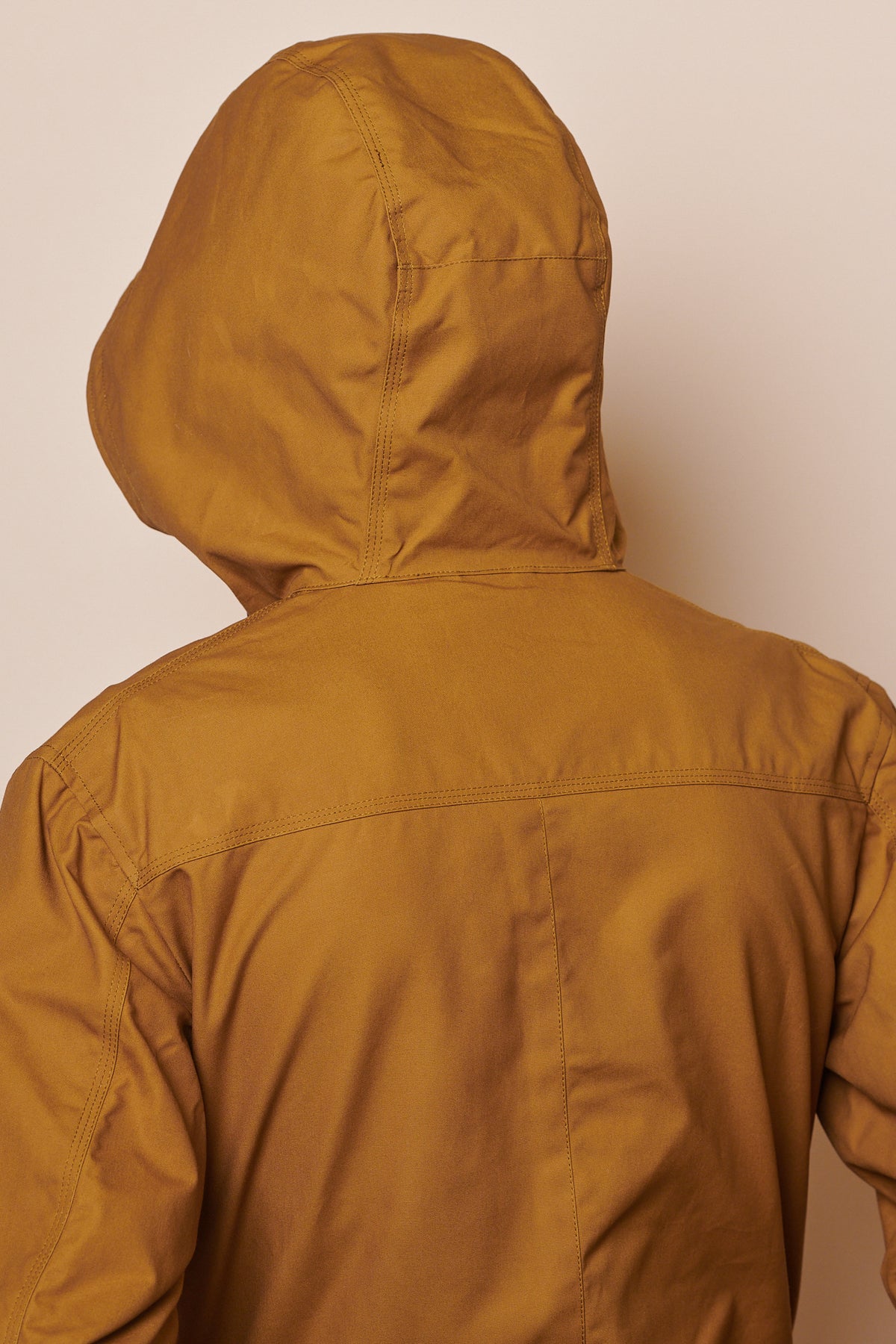 Back of male wearing hood up of mountain parka in tan
