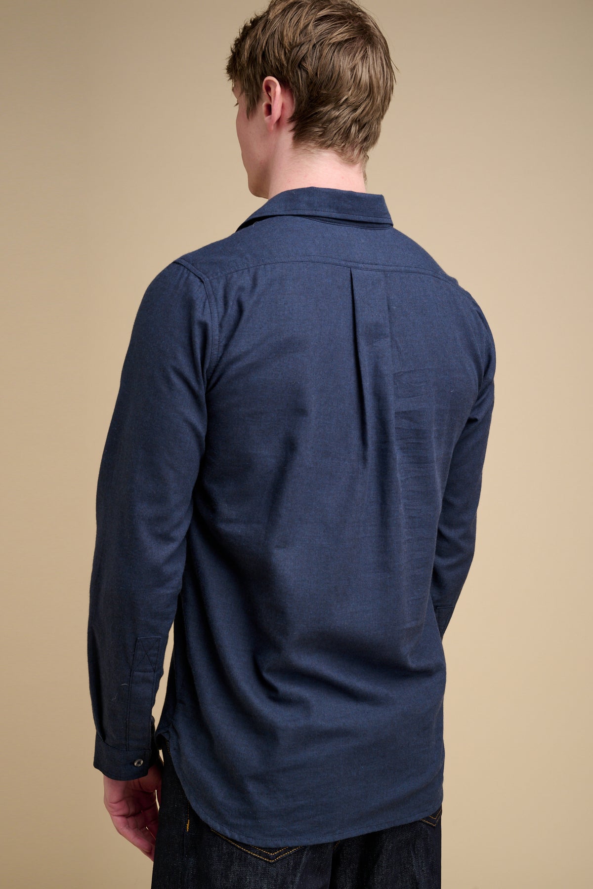 The back of man wearing a navy blue half placket long sleeve shirt.