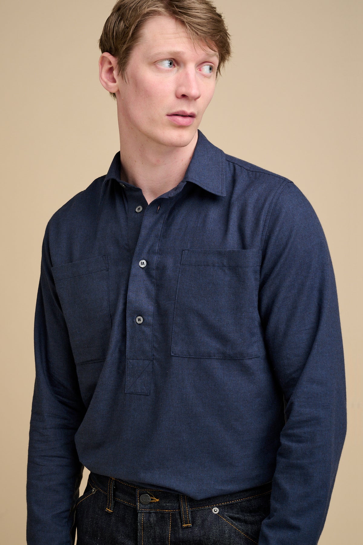 Man wearing a navy blue half placket long sleeve shirt.