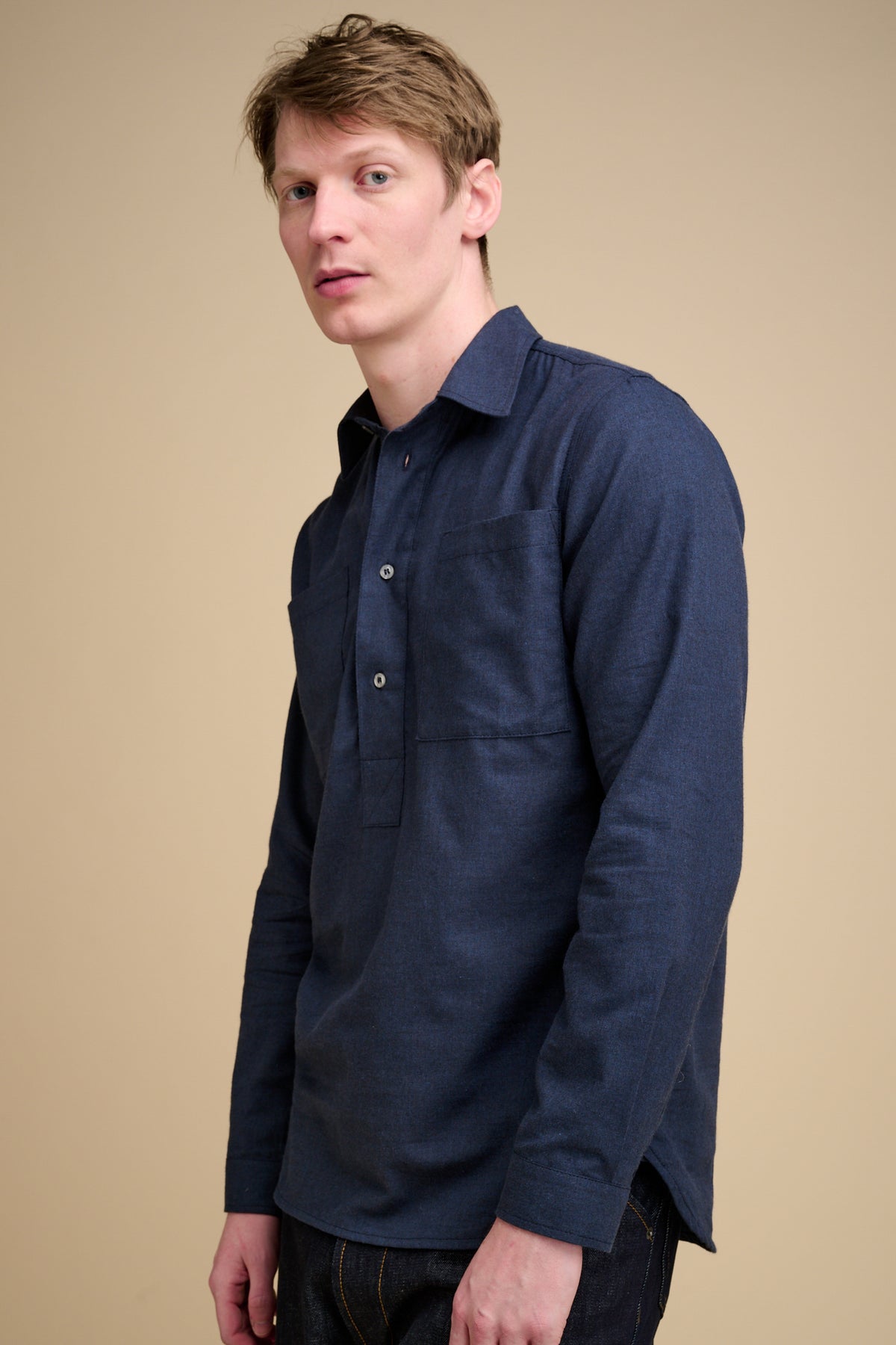 Man wearing a navy blue half placket long sleeve shirt.