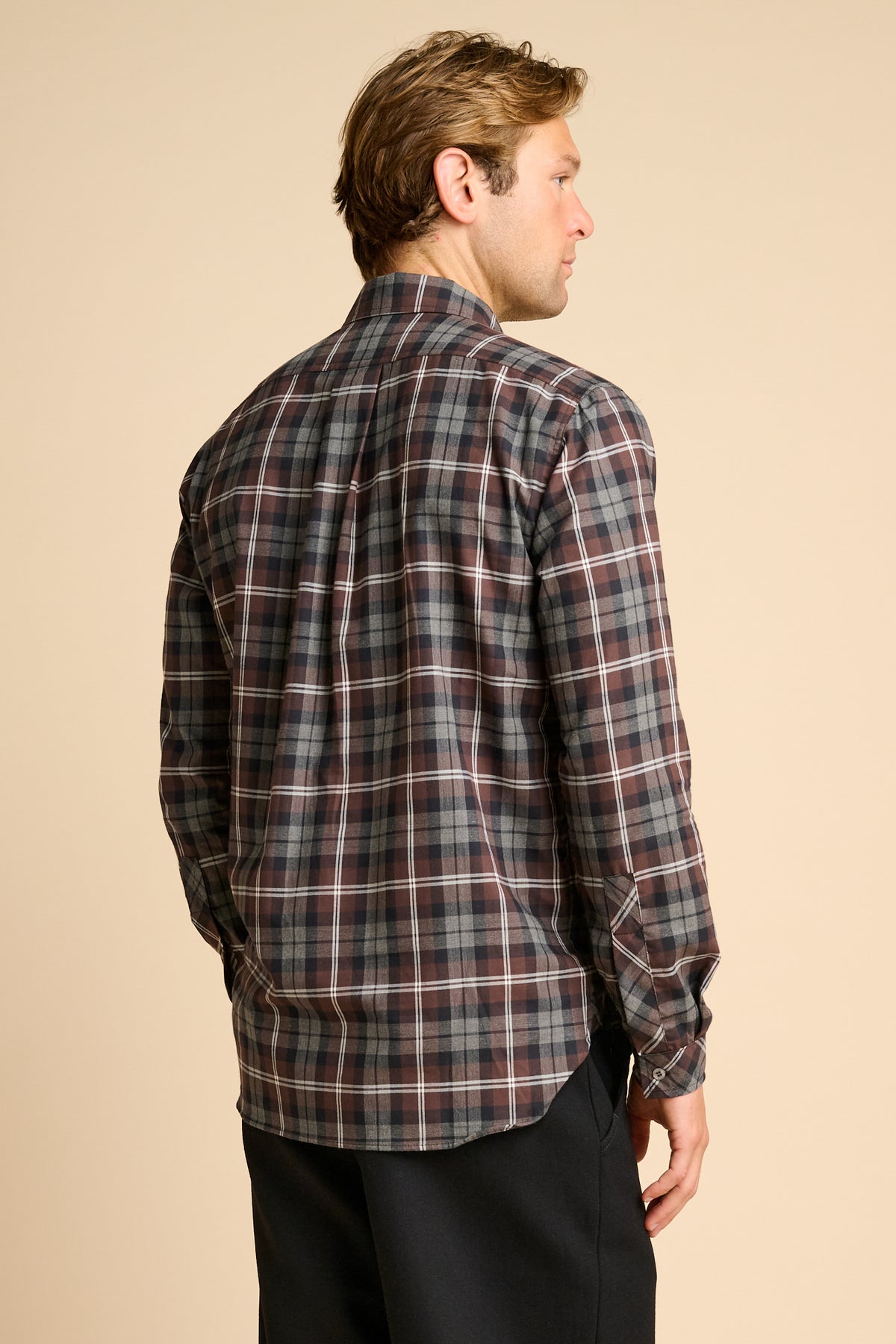 Man wearing check shirt against beieg background.