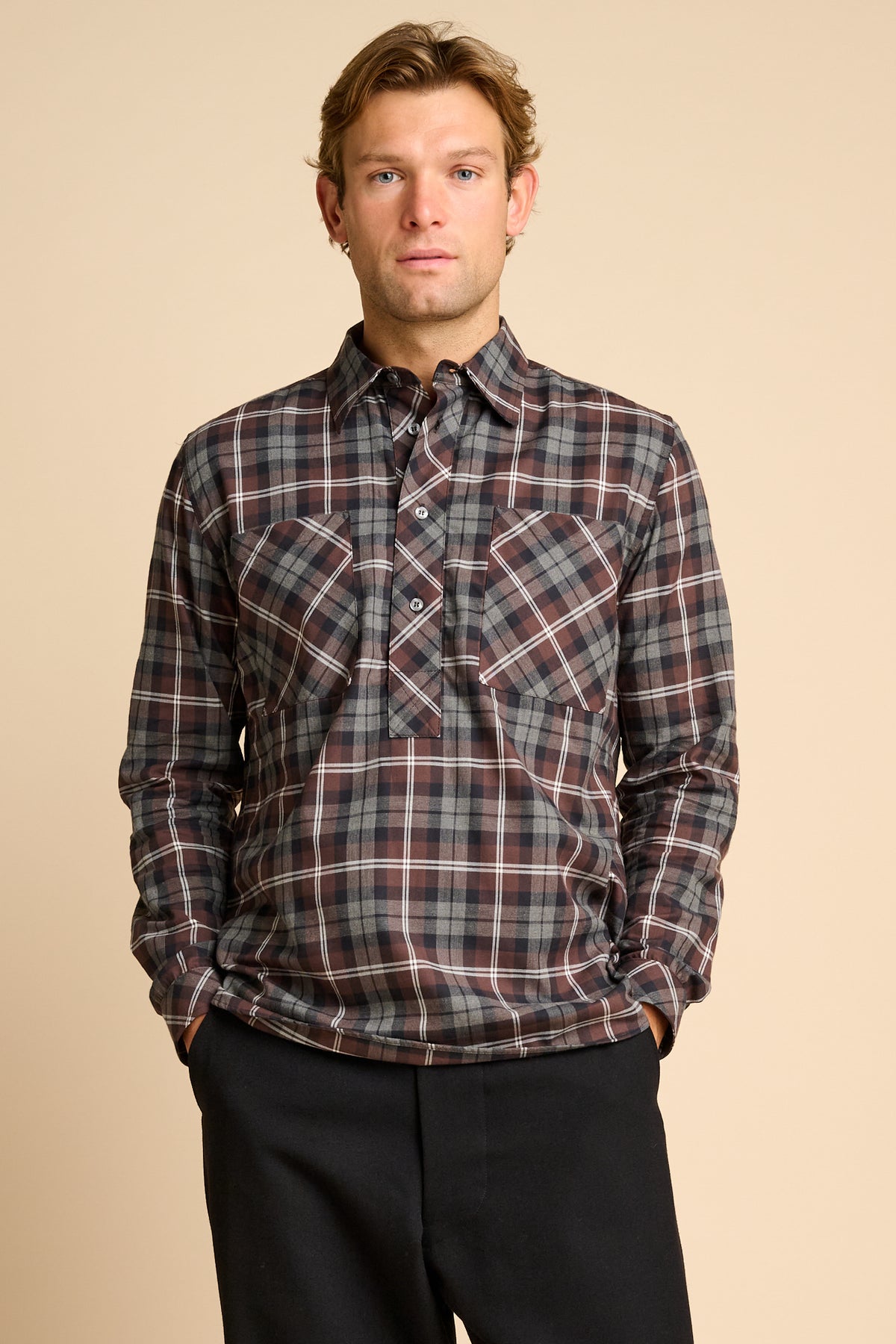 Man wearing check shirt against beieg background.