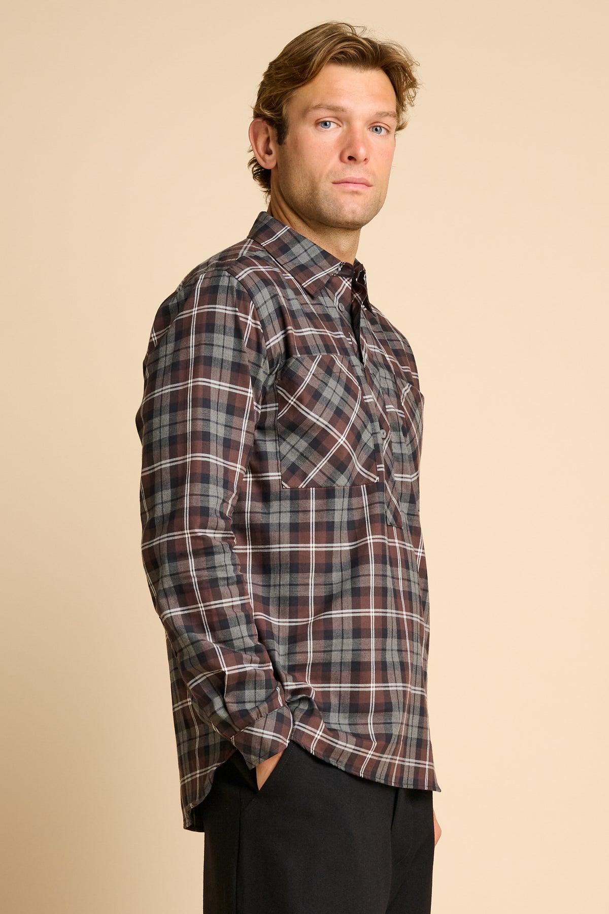 Man wearing check shirt against beieg background.
