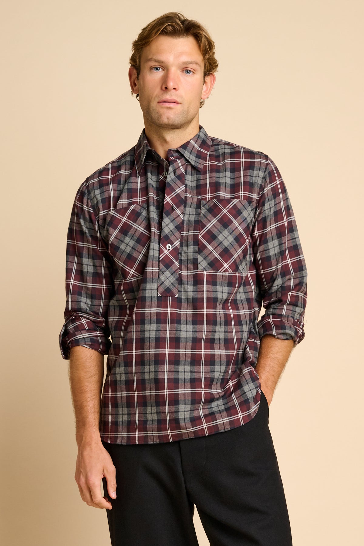 Man wearing red check shirt against beige background.