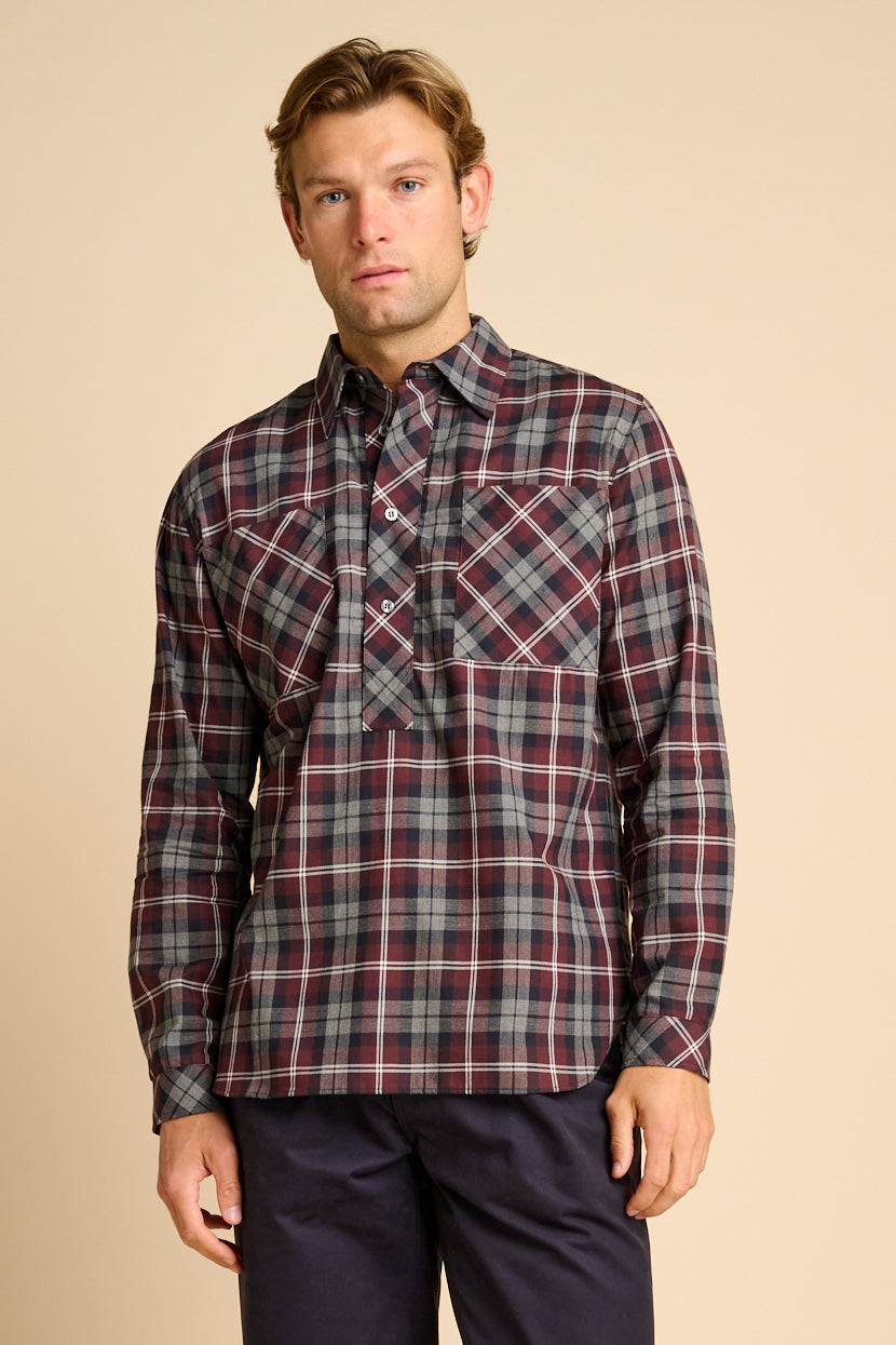 Man wearing red check shirt against beige background.