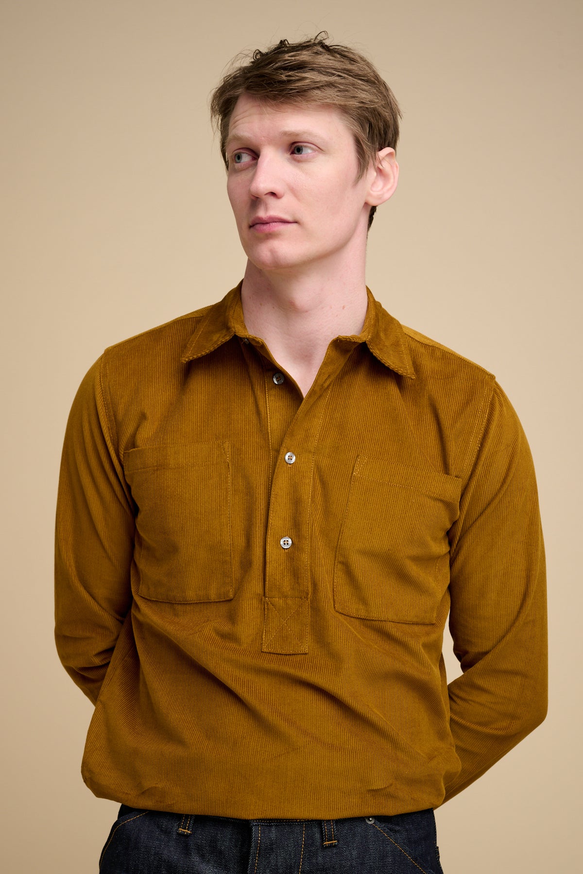 The back of man wearing half placket needle cord shirt in mustard.