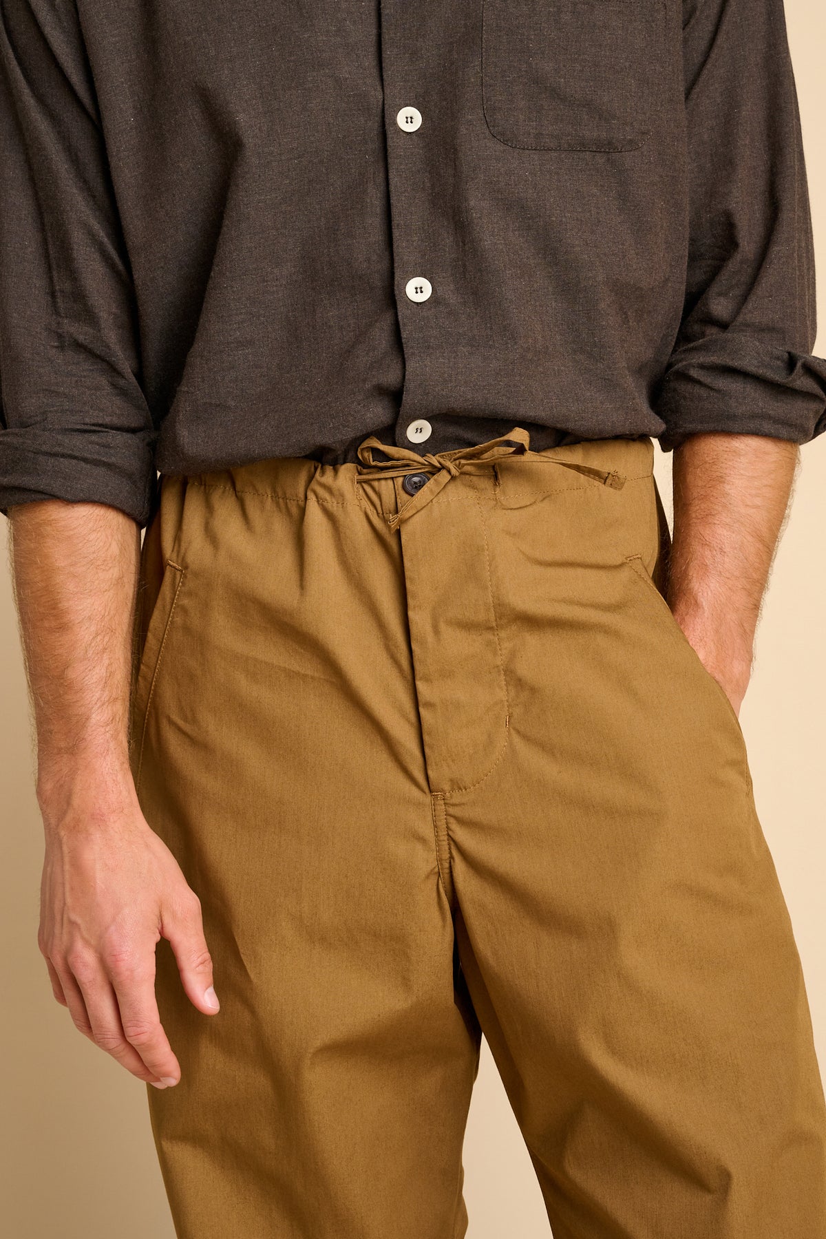 Man wearing tan trousers with brown shirt.