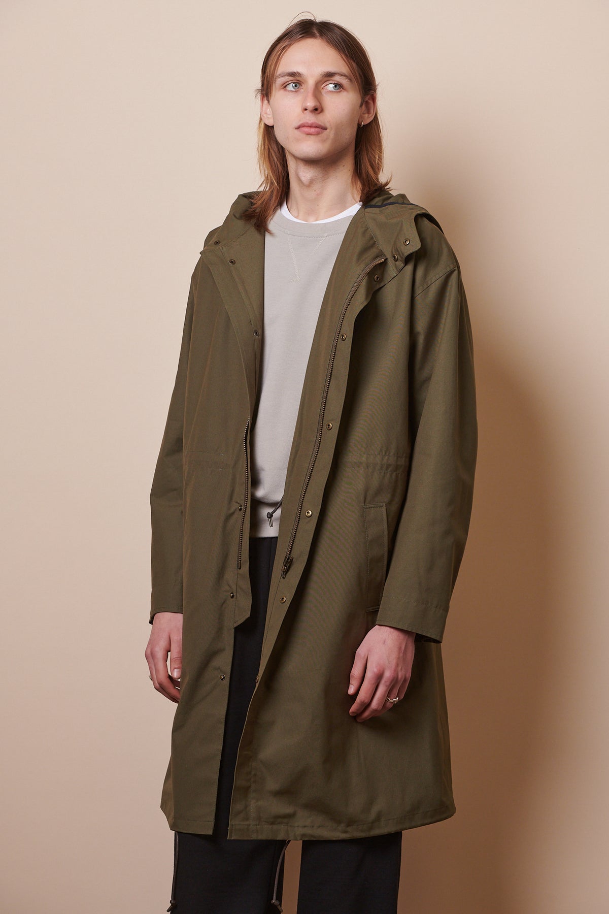 Knee up image of male wearing parka in olive unzipped 