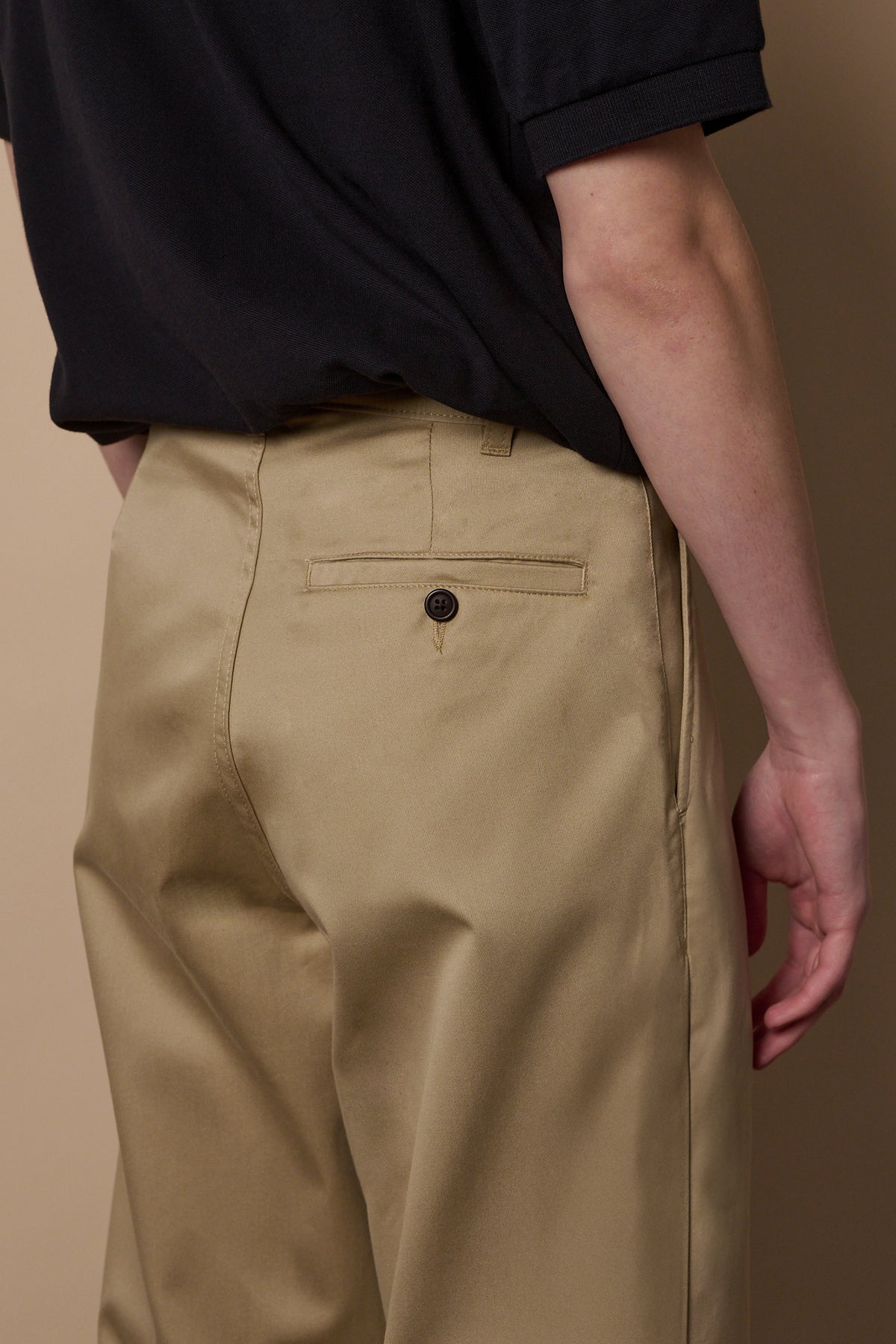 Detail of back pocket with button on the pleated chino in stone 