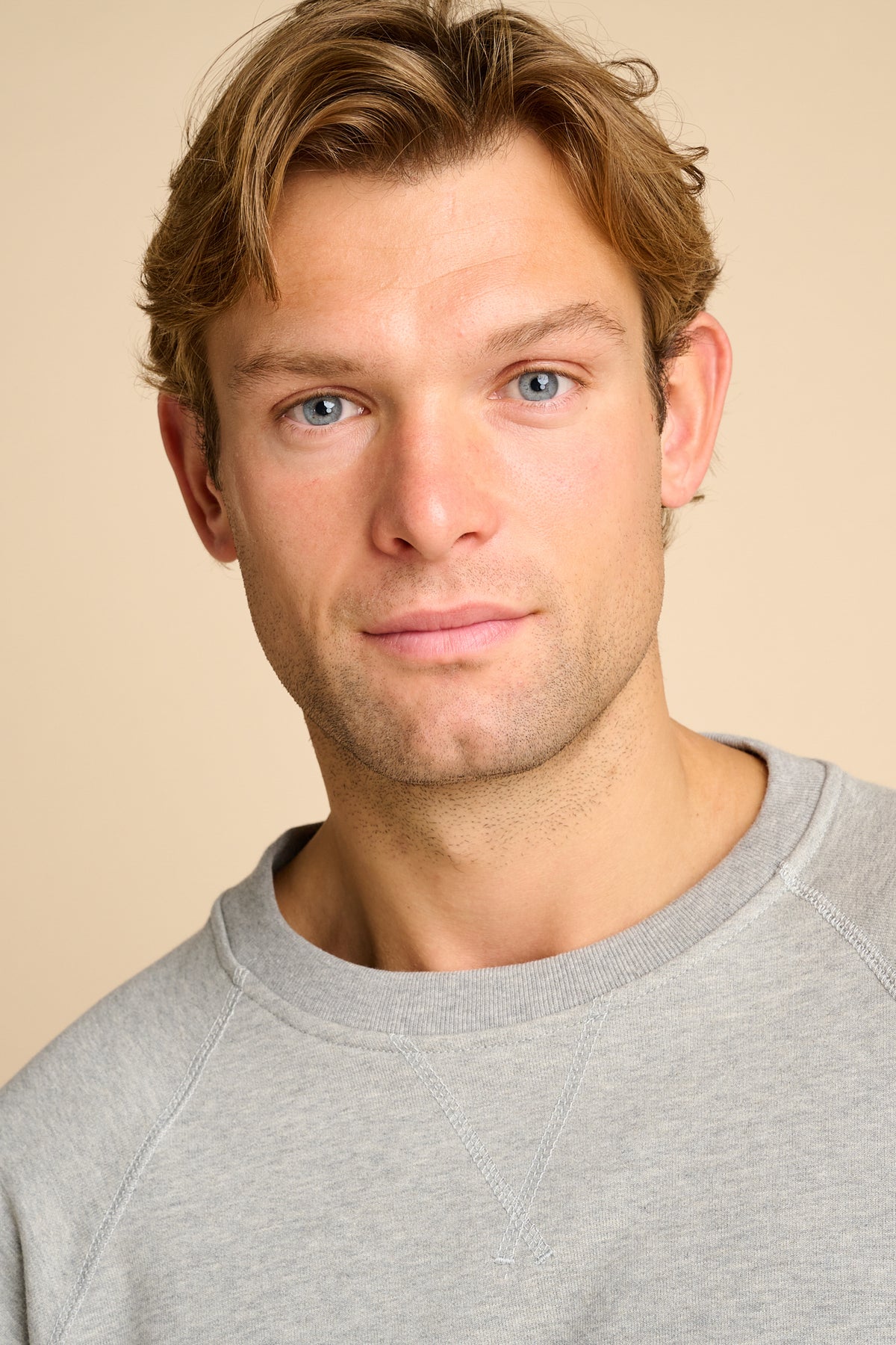 Man wearing a grey sweatshirt on a beige background