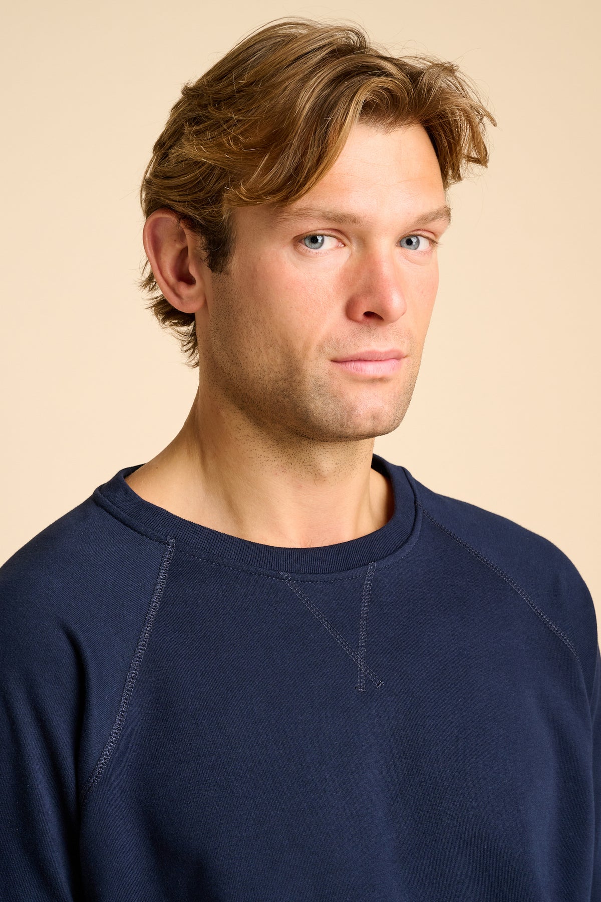 Man wearing a navy blue sweater against a beige background