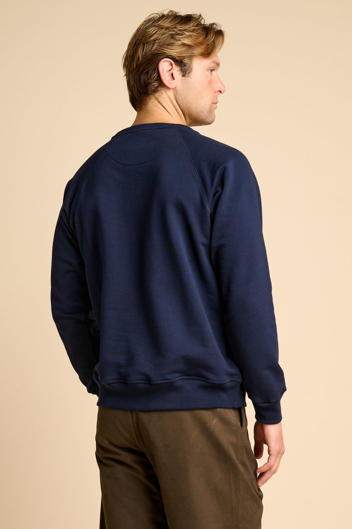 Man wearing a navy blue sweatshirt on a beige background