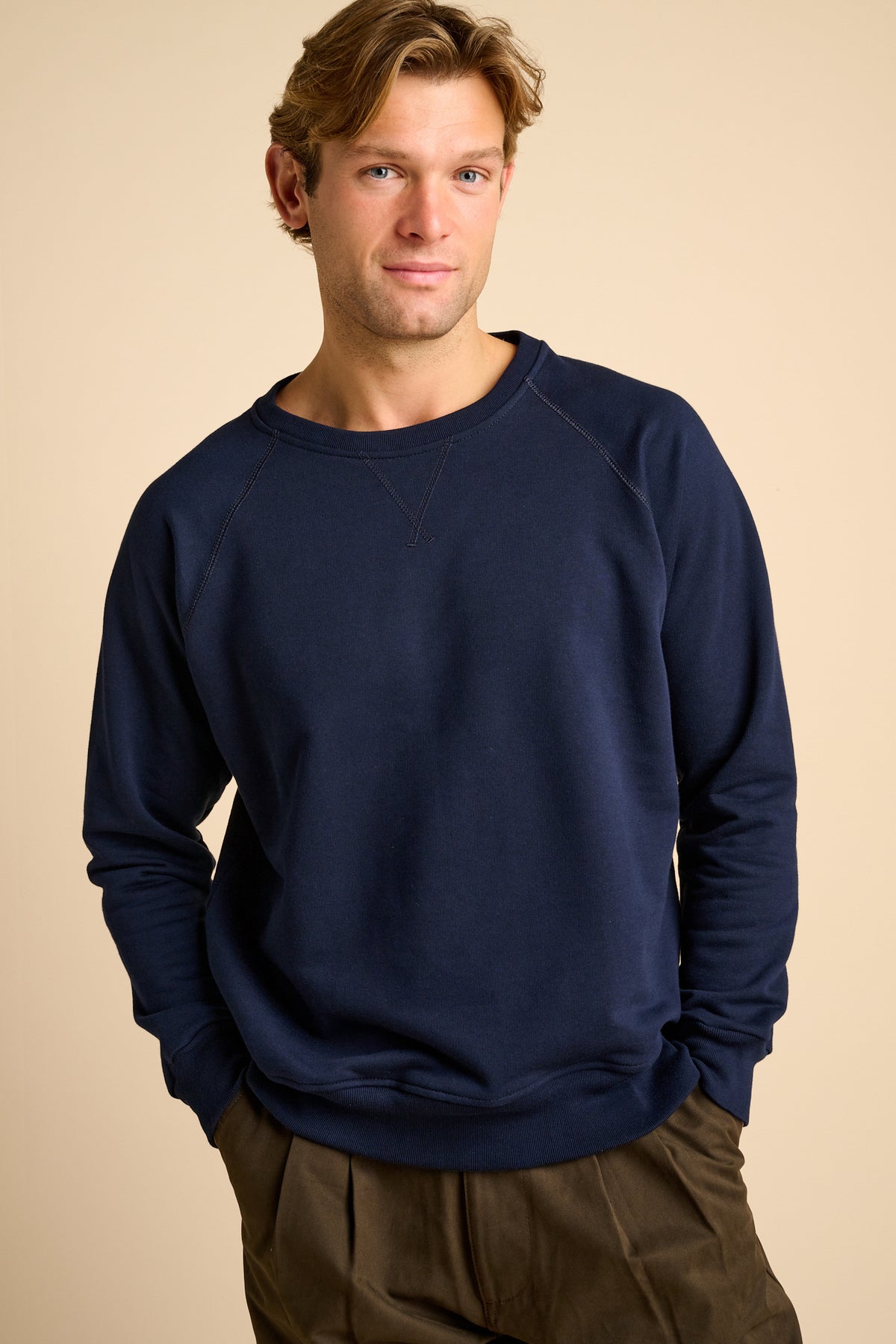 Man wearing a navy blue sweatshirt against a beige background.