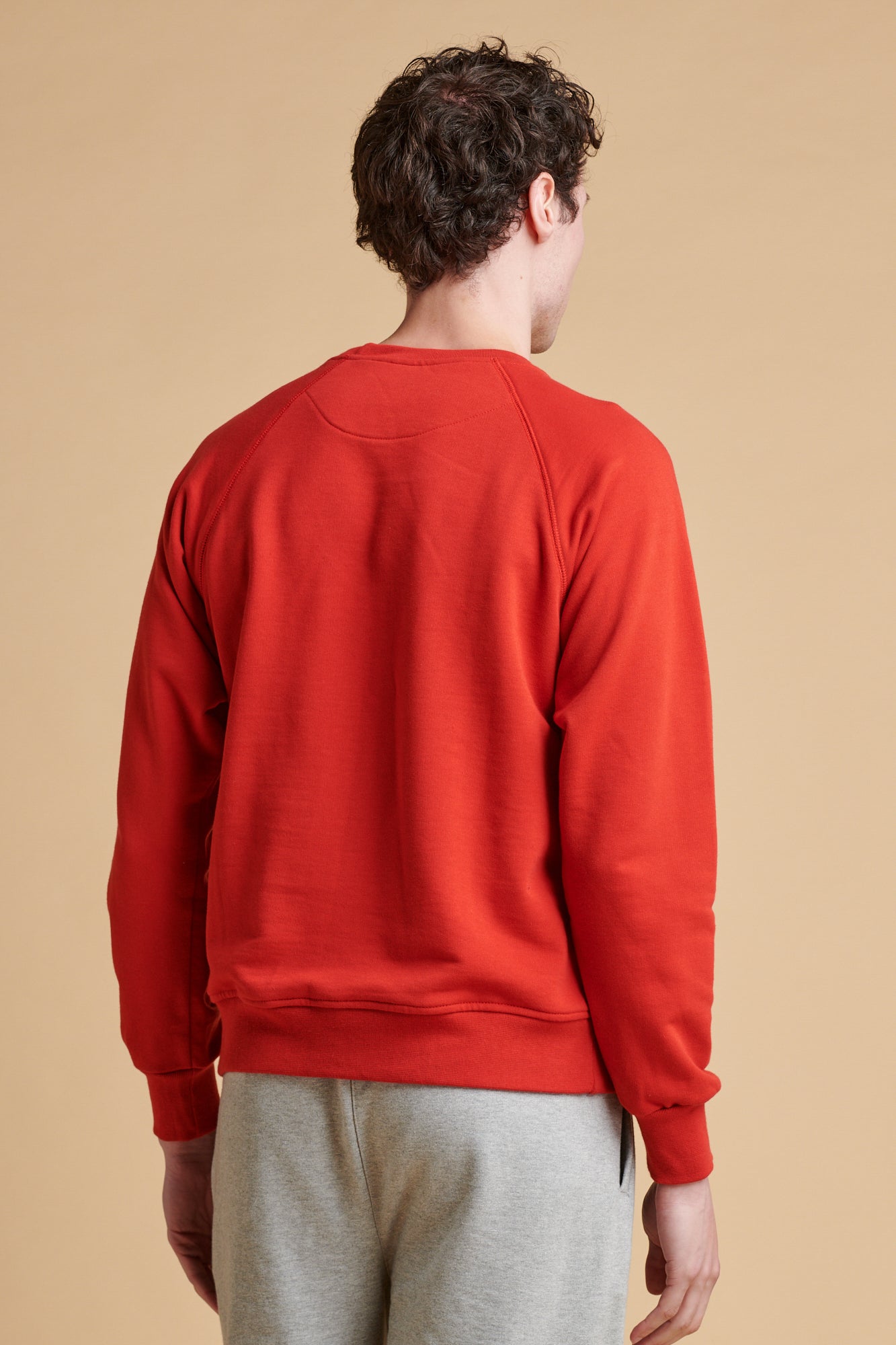 Thigh up of male wearing raglan sweatshirt in crimson.