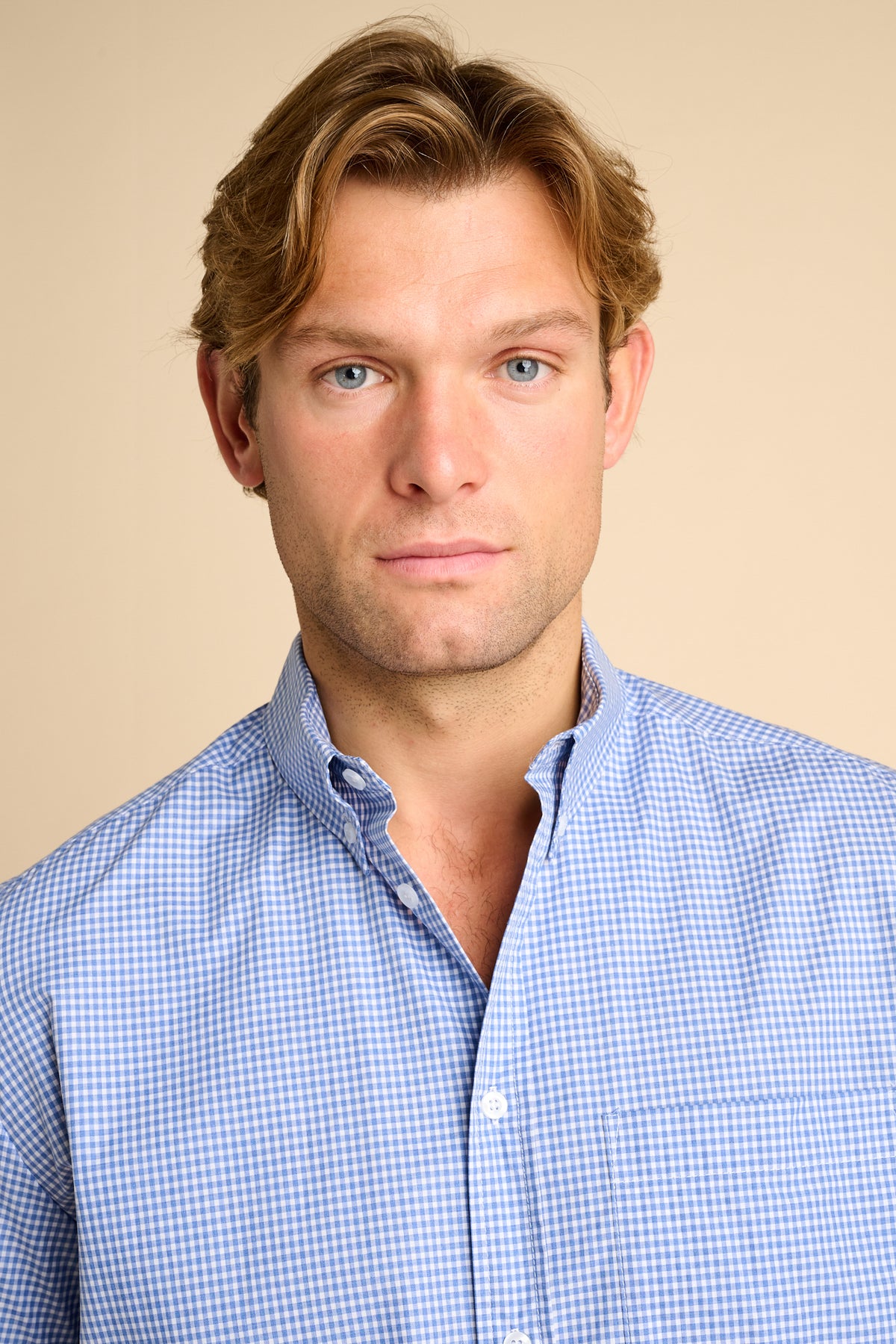 Man wearing a blue checkered shirt against a beige background