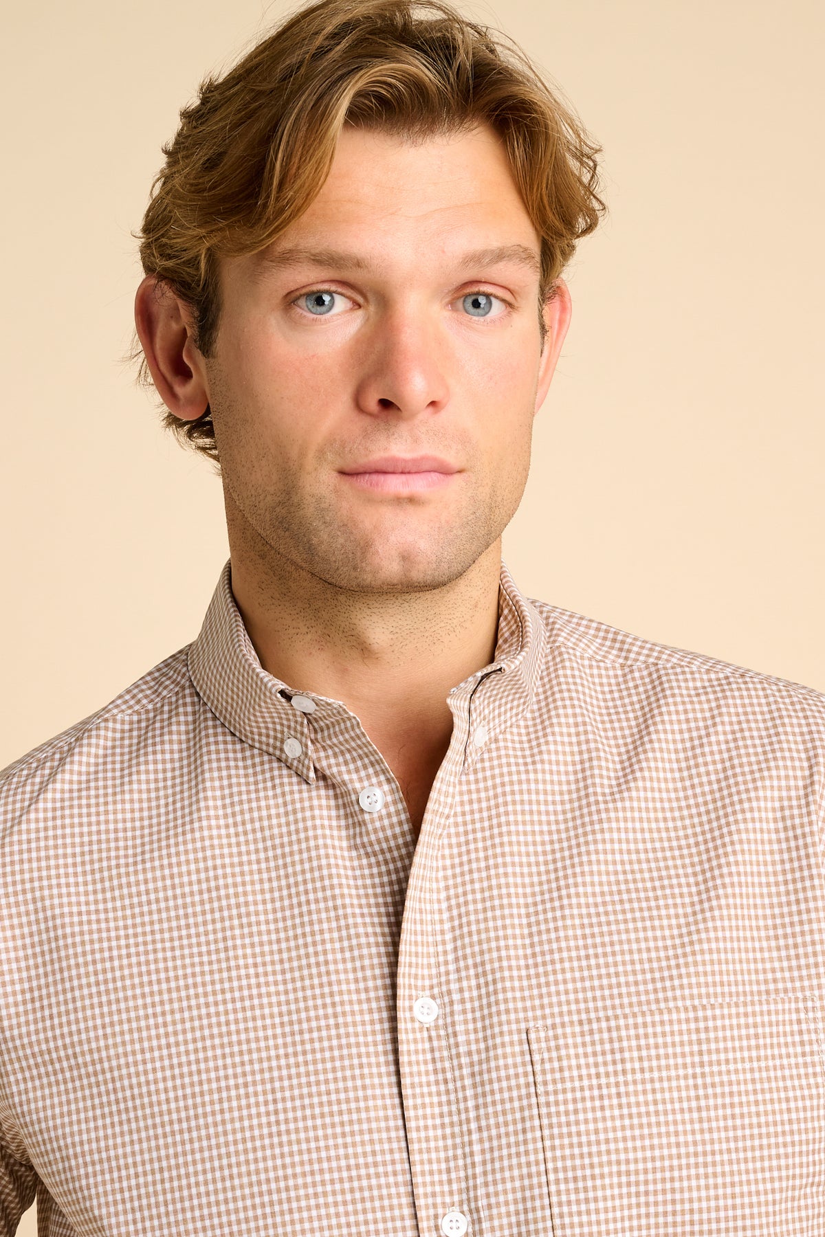 Man wearing a checkered shirt against a beige background