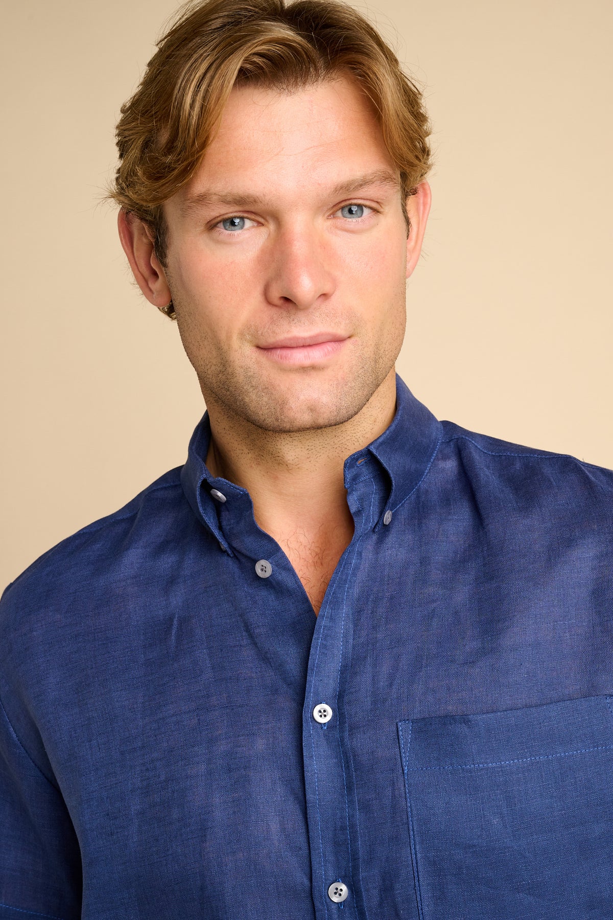 Man wearing a blue shirt on a beige background.
