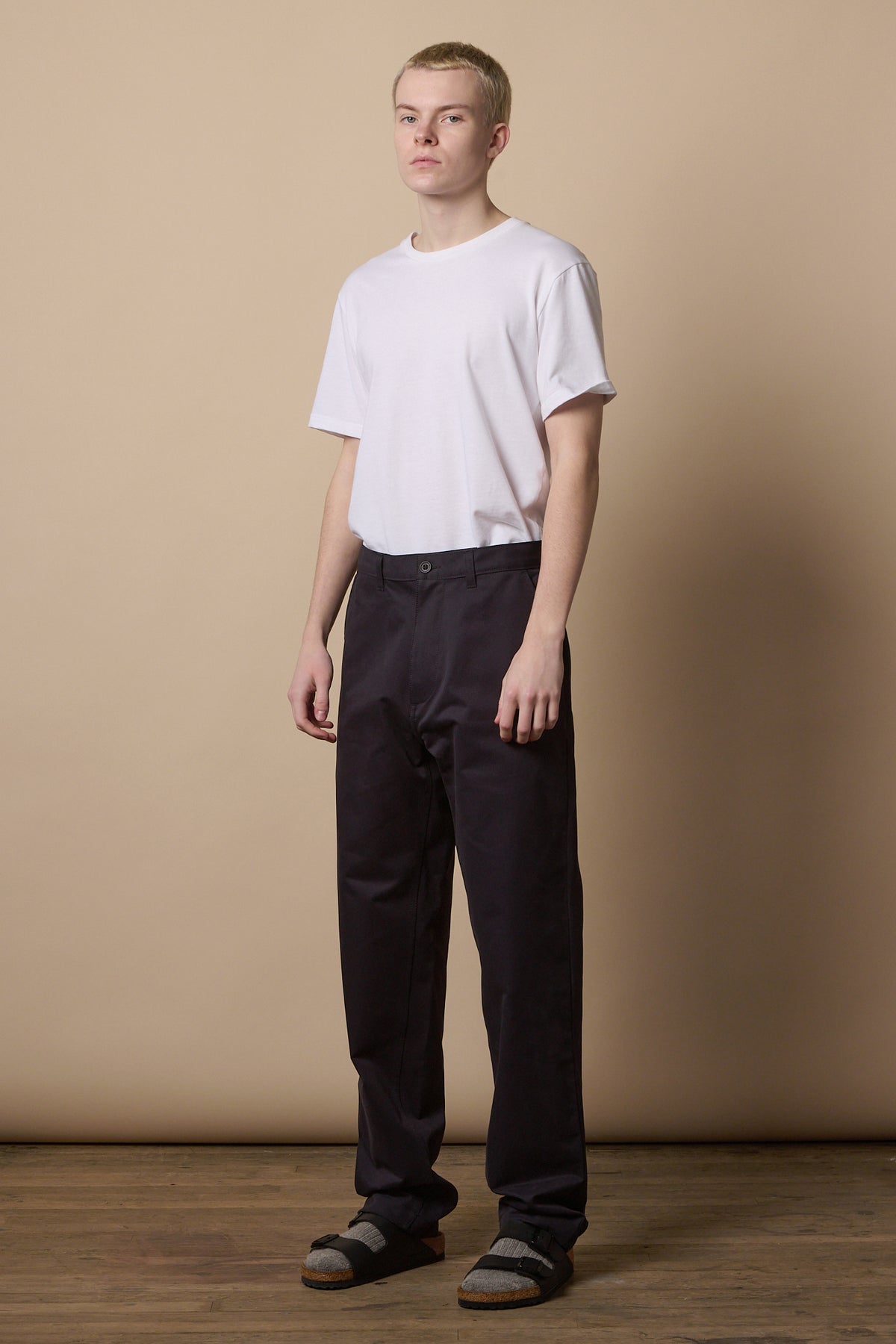 Full body image of male wearing men's relaxed chino in navy worn with short sleeve crew neck white t shirt 