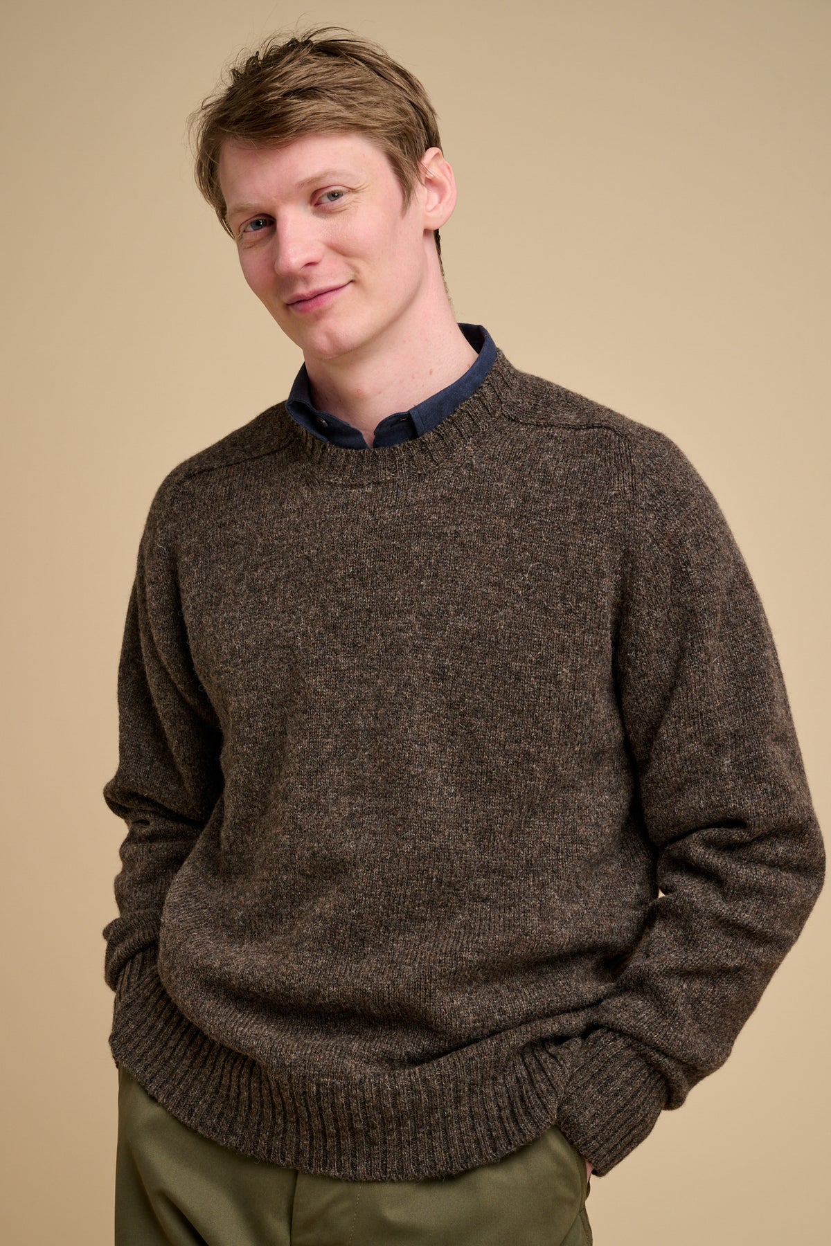 Man wearing a brown sweater against a beige background