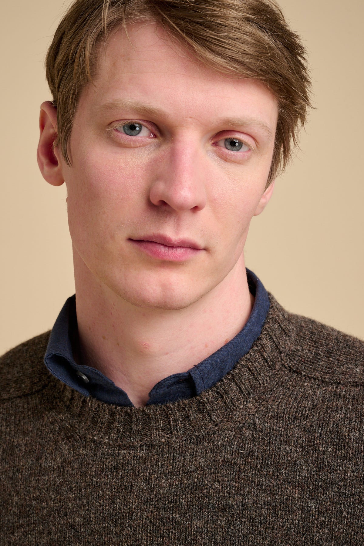 Man wearing a brown sweater with a beige background