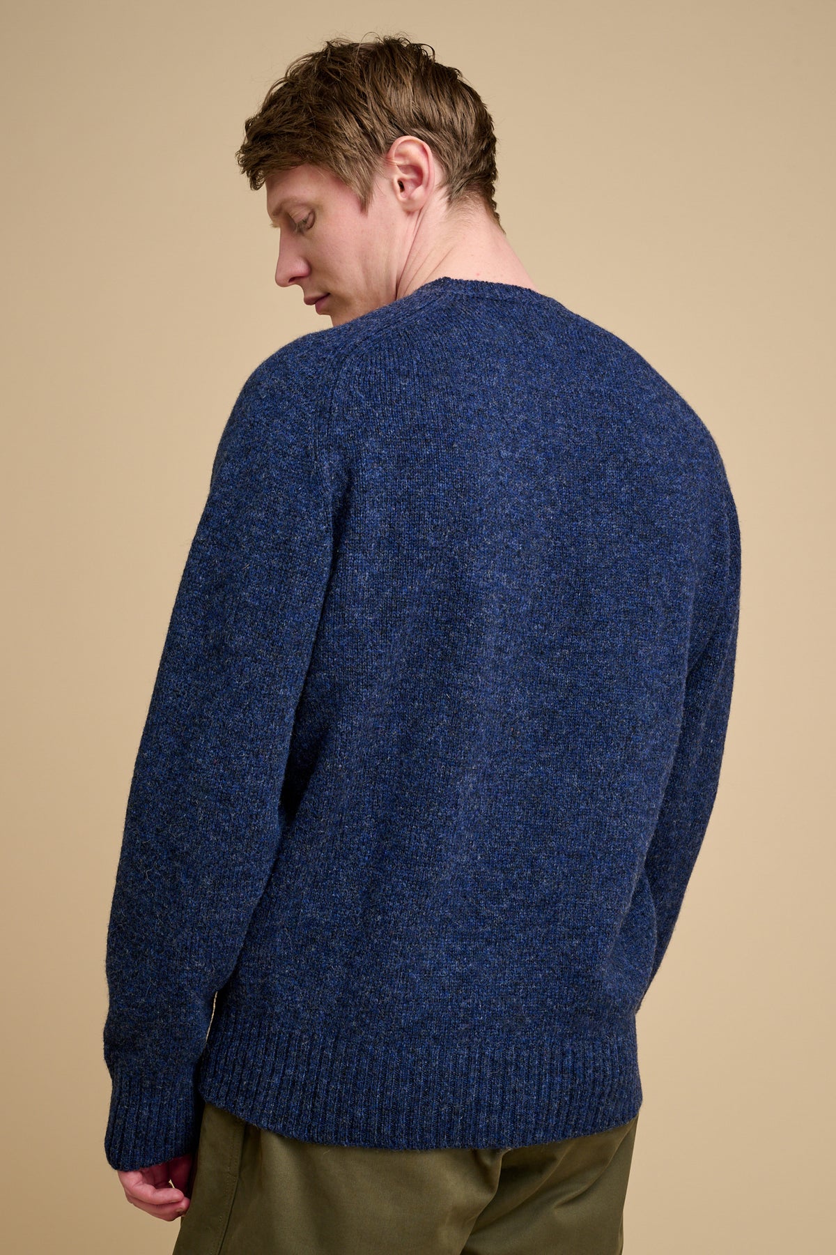 Man wearing a blue sweater against a beige background