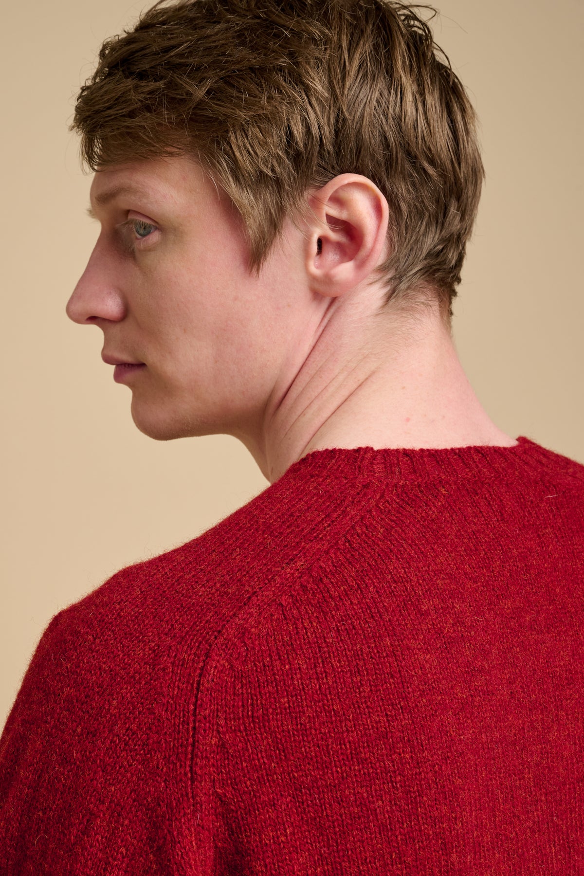 Person wearing a red sweater against a beige background