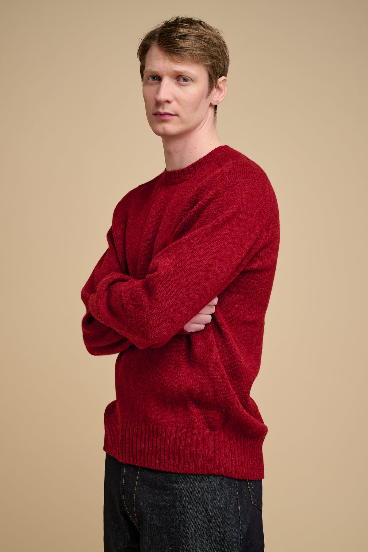 Man wearing a red sweater against a beige background