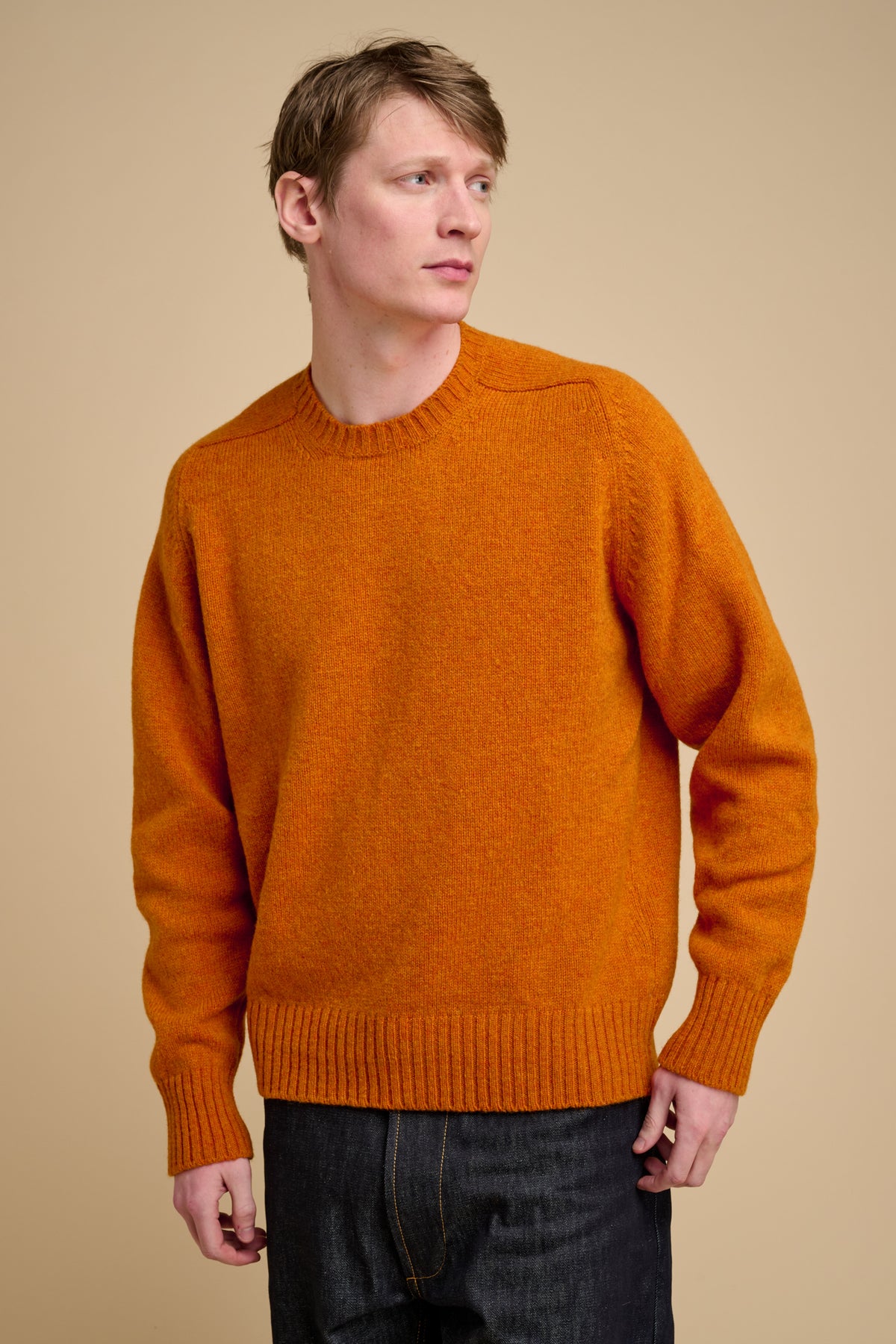 Man wearing an orange sweater against a beige background