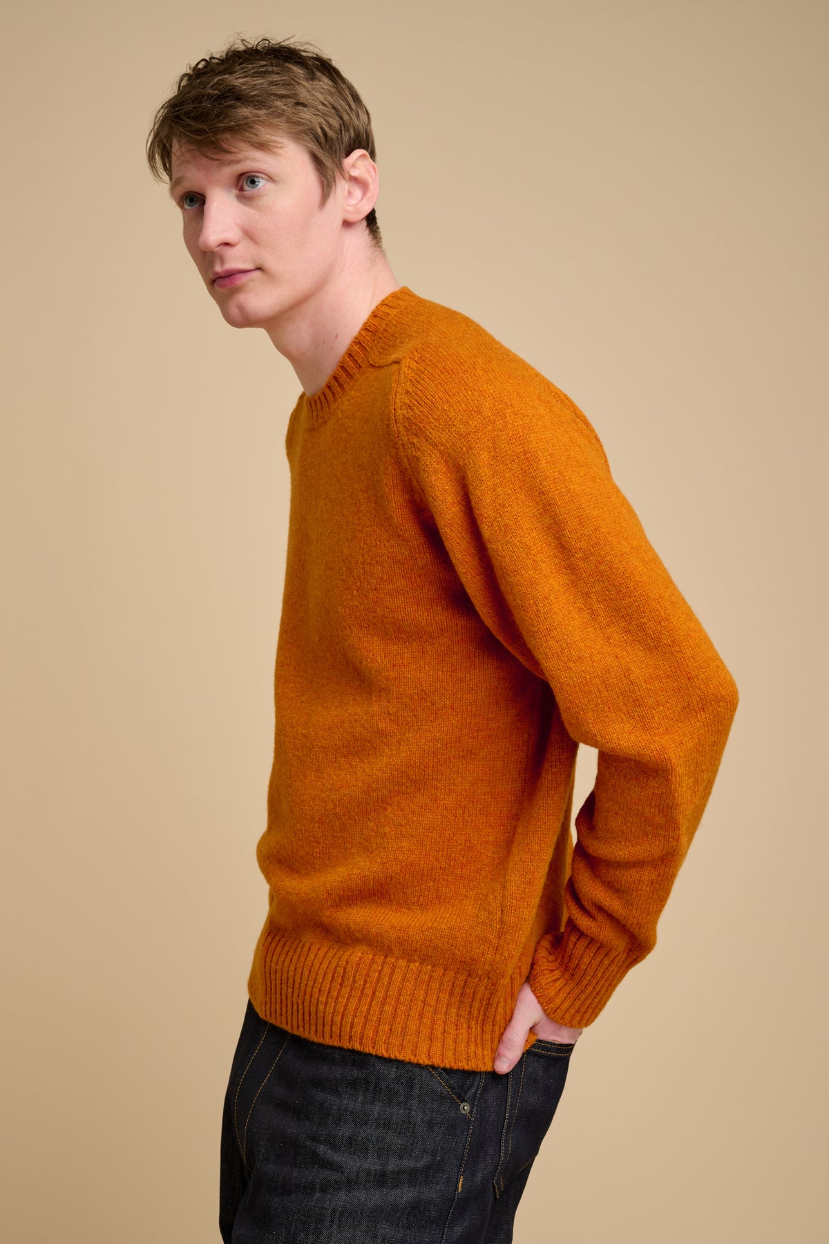Man wearing an orange sweater against a beige background