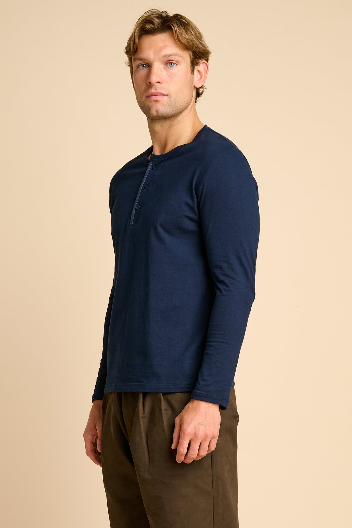 Man wearing a navy long-sleeve shirt against a beige background.