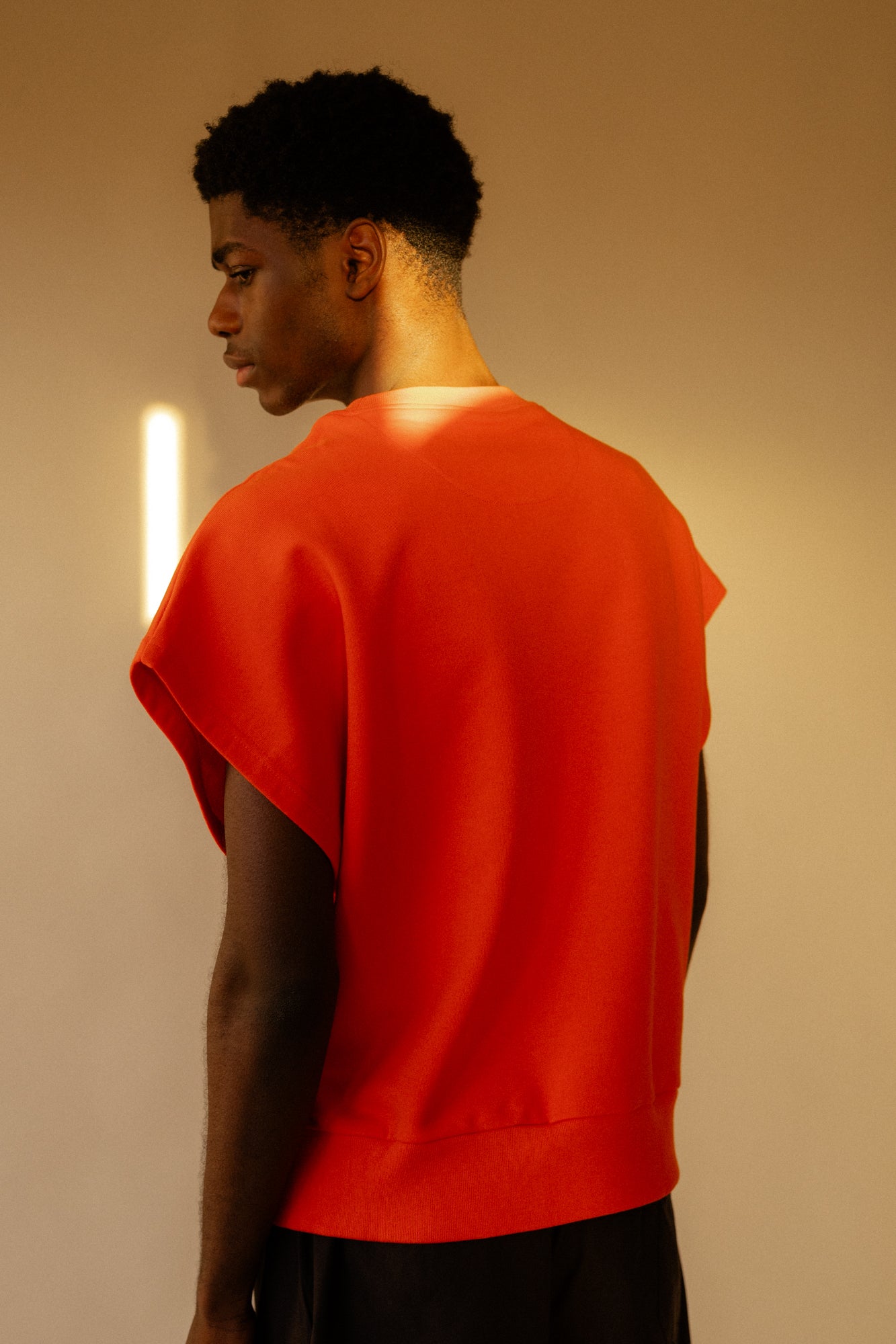 Image of the back of male wearing sleeveless sweatshirt plastic free in flame red 