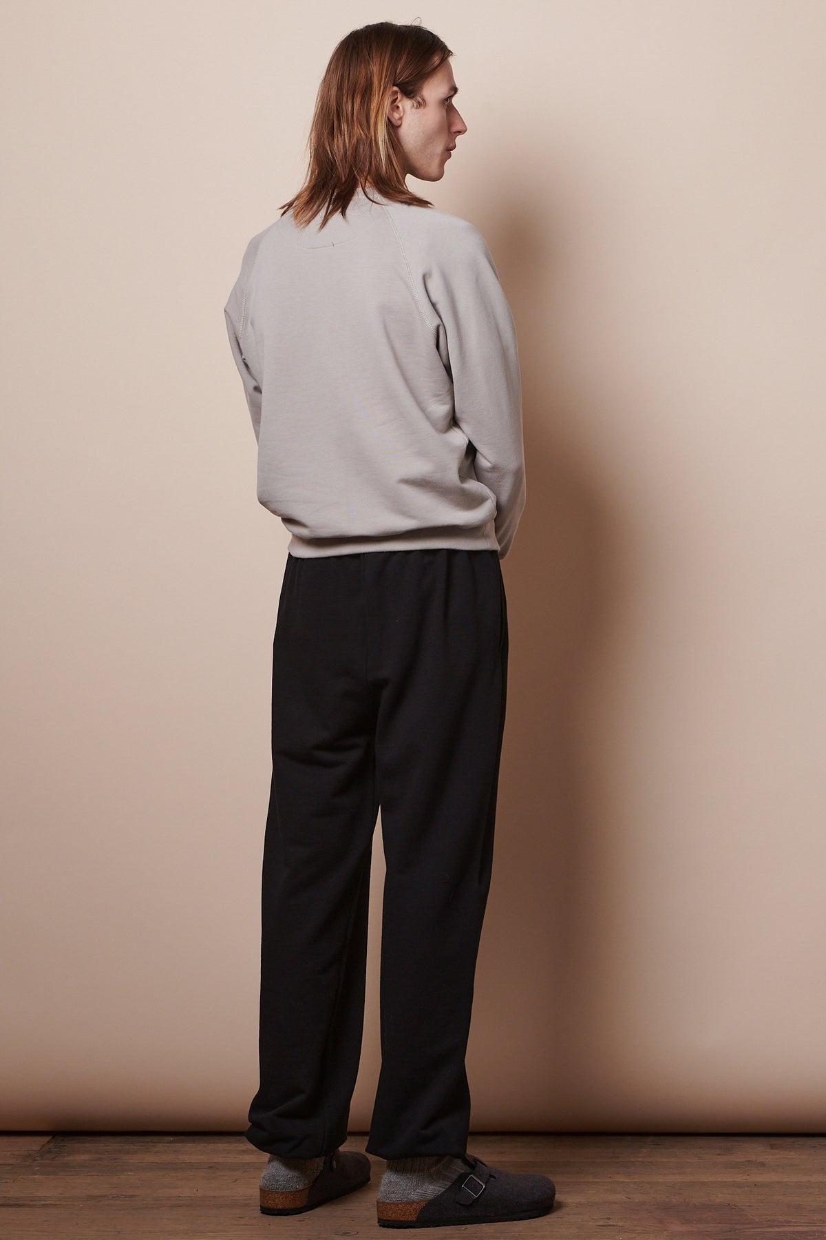 back of male wearing black sweatpants with raglan sweatshirt in stone