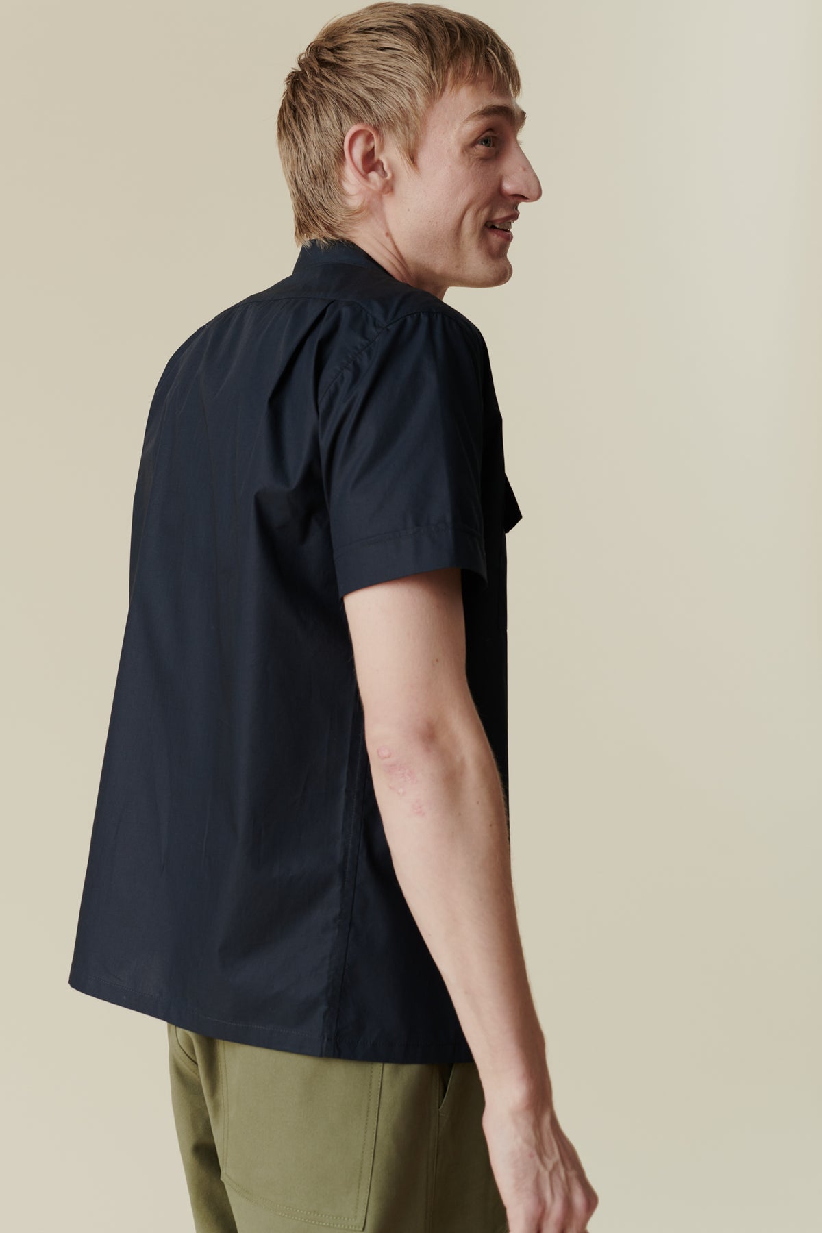 Back of white male wearing tom short sleeve military shirt with olive cameraman pants