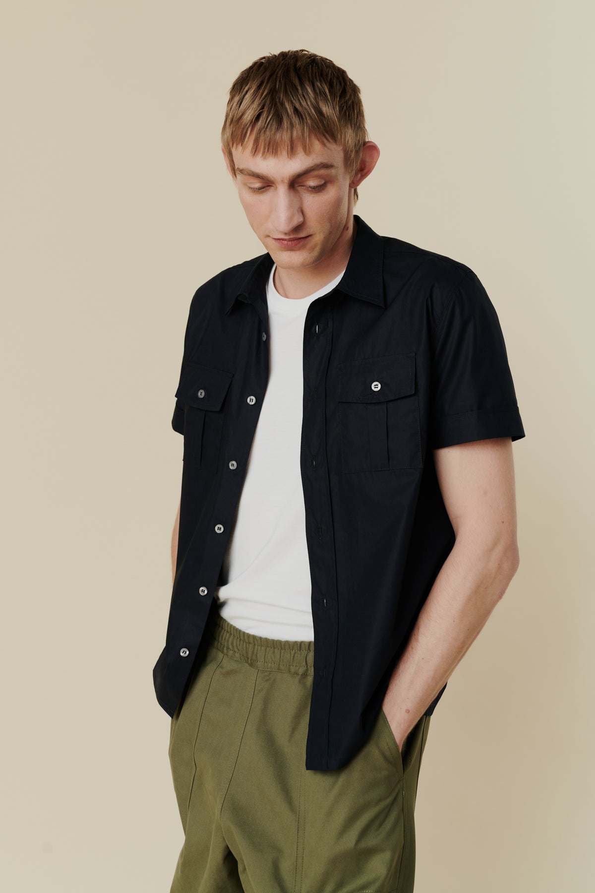 Tom short sleeve military shirt in navy unbuttoned over white short sleeve crew neck t shirt with olive cameraman pants