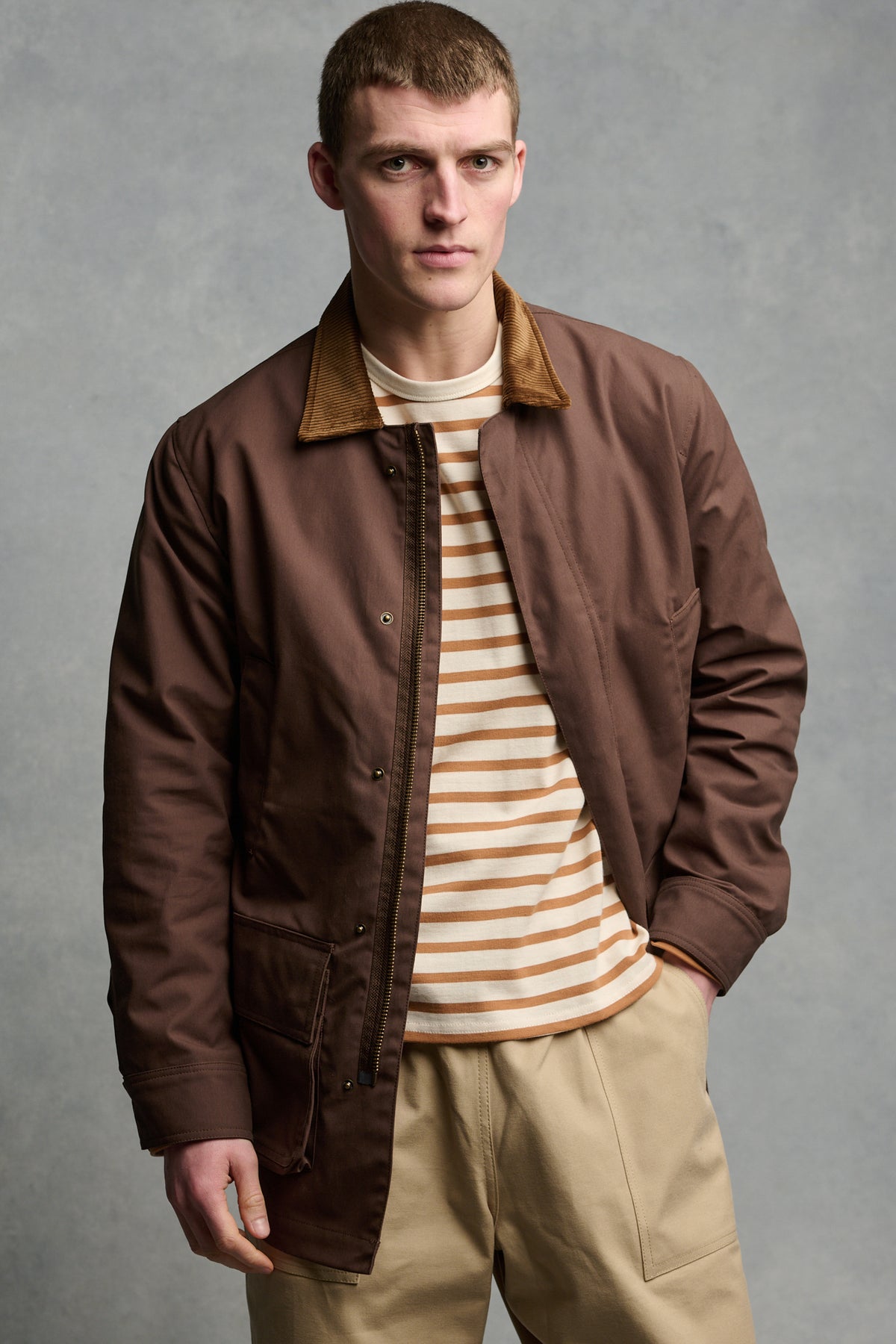 Male wearing brown barn jacket unzipped over stripe top.