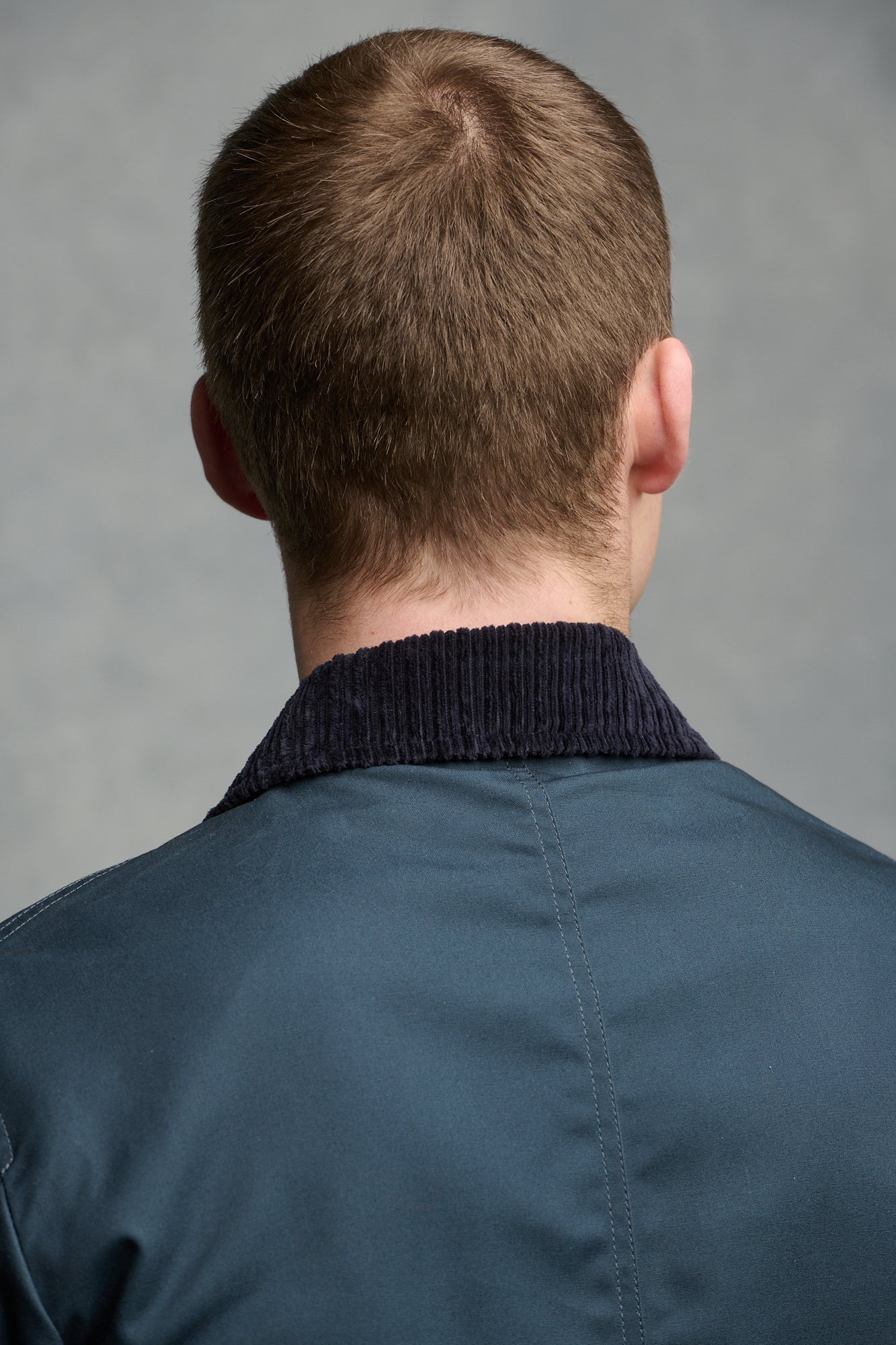 Thigh up image of brunet male wearing barn jacket in navy unzipped open over Breton in charcoal and grey marl
