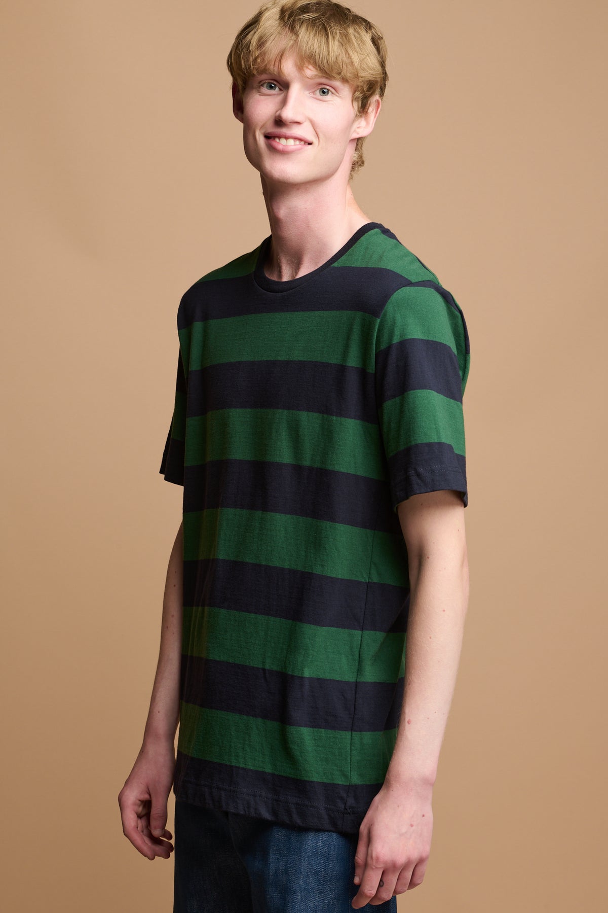 The side of smiley male wearing wide stripe t shirt in green navy 