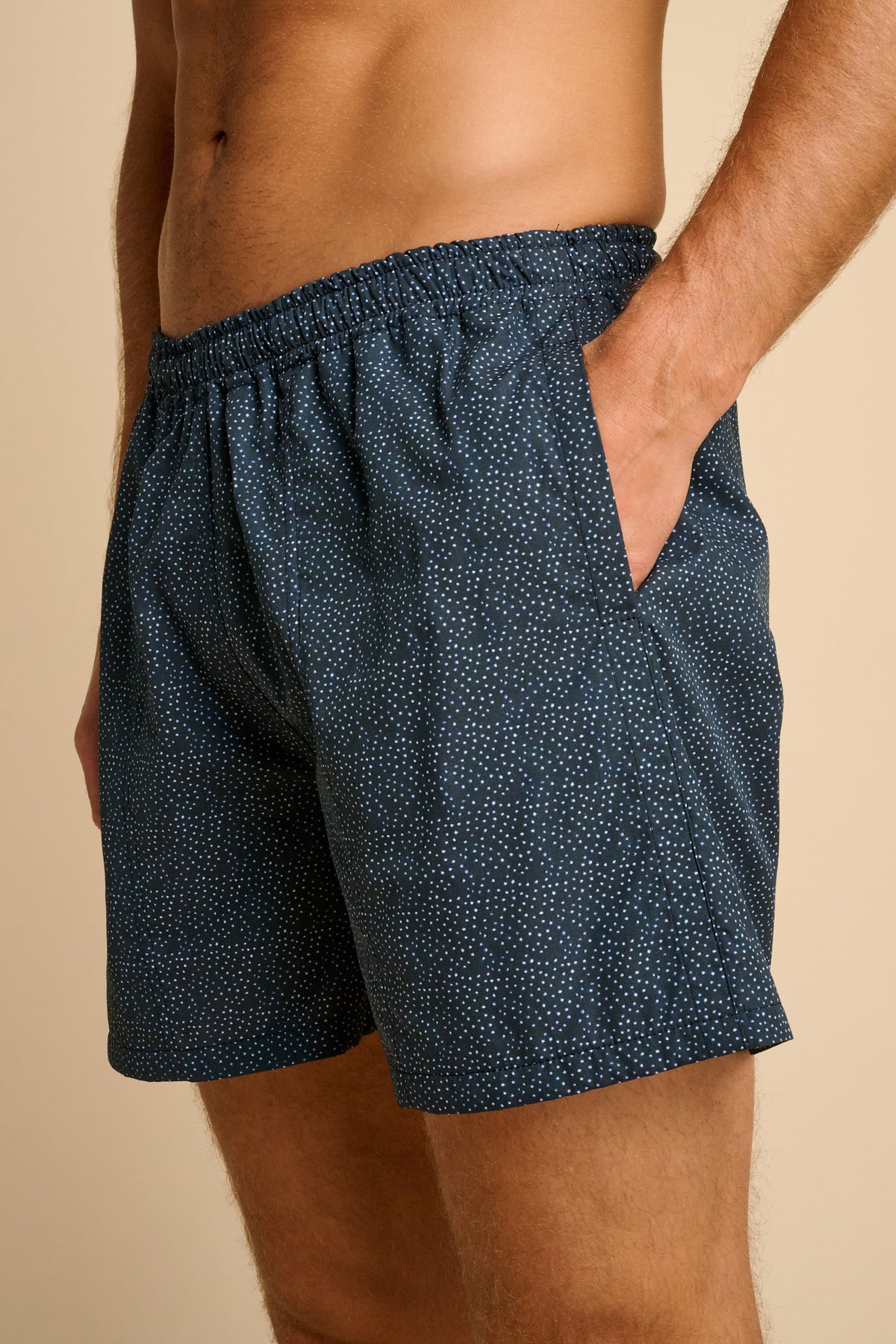 Navy patterned shorts worn by a person on a beige background