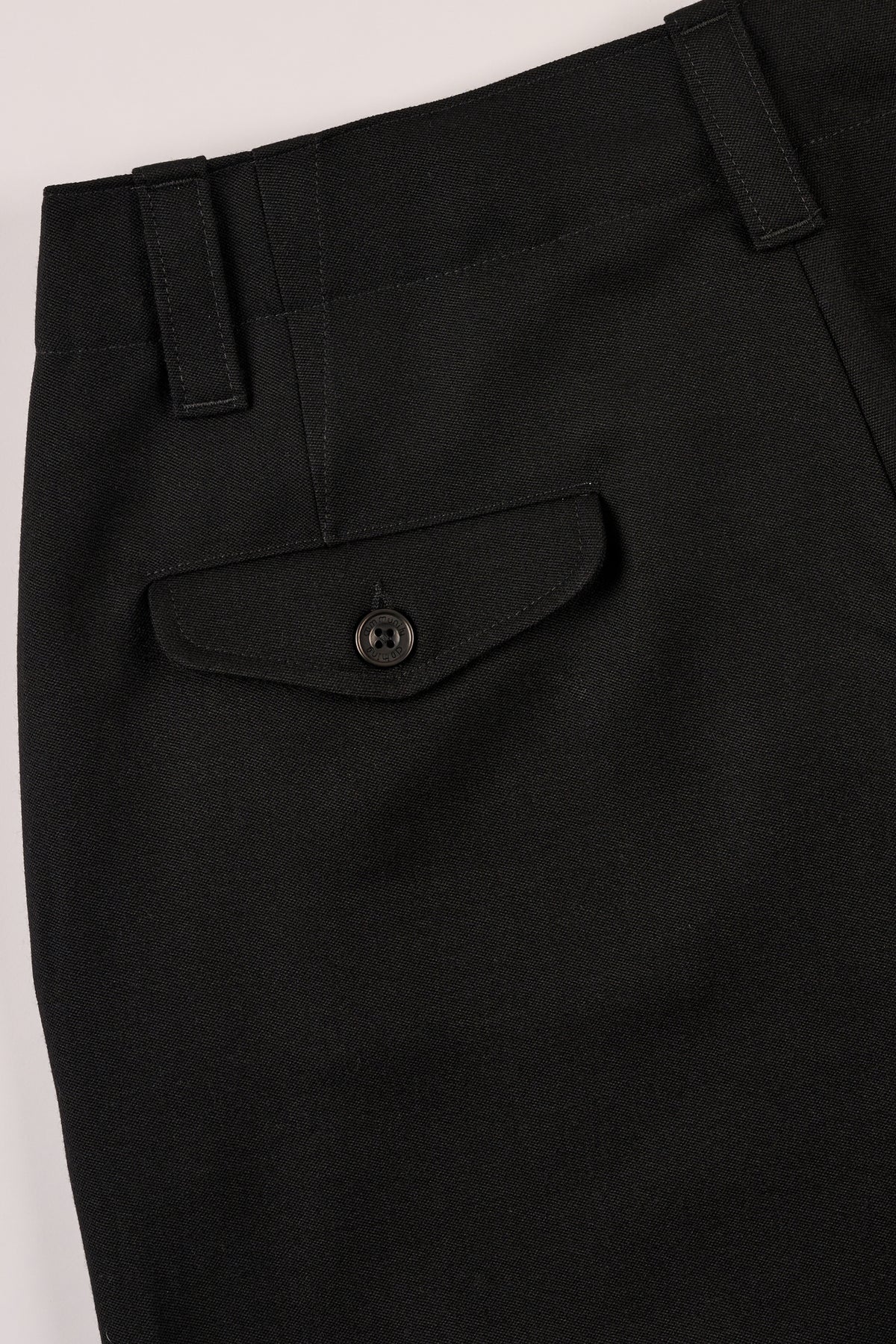 Close-up of black pants with a pocket and button
