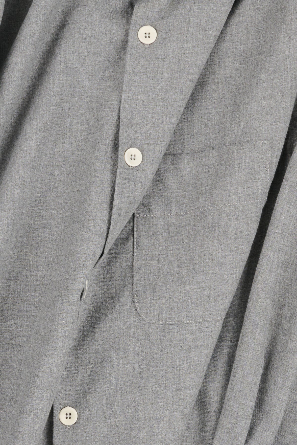 Close-up of a grey textured shirt with buttons and a pocket.